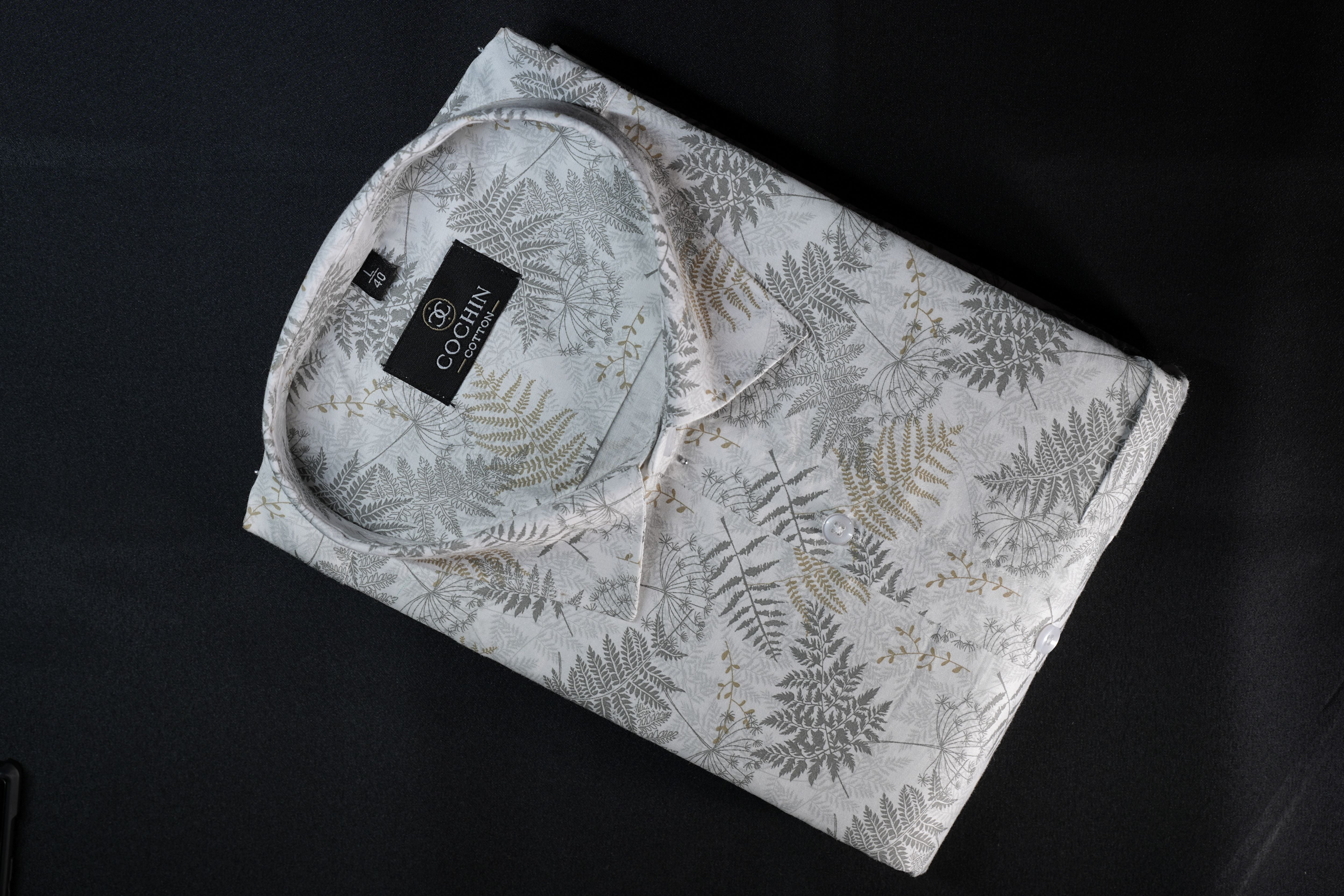 Folded shirt with fern leaf pattern on a dark surface