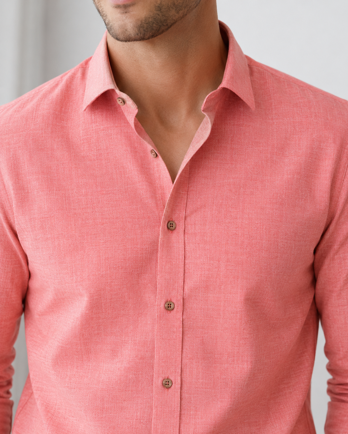 Close-up of a person wearing a pink button-up shirt against a neutral background