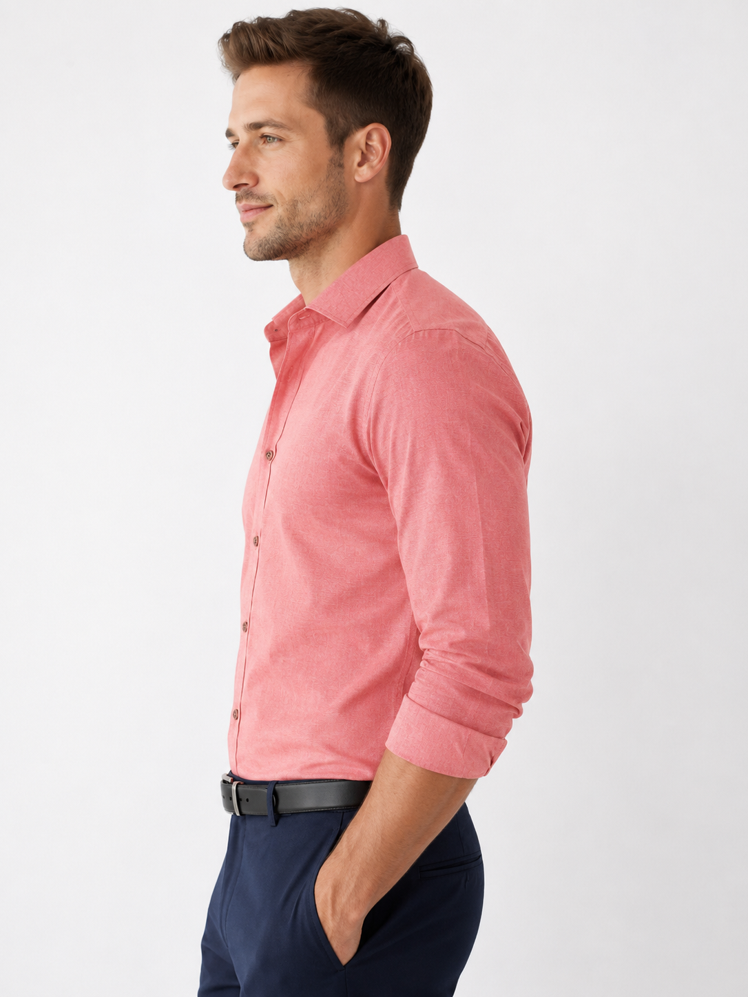 Man wearing a pink shirt and dark pants on a white background