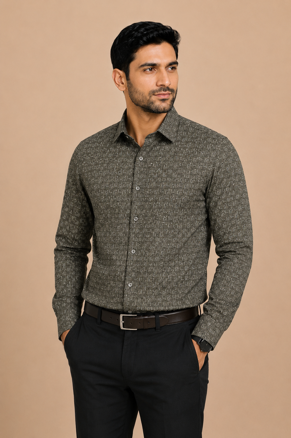 A man wearing a textured gray long-sleeve button-down shirt with a subtle geometric pattern, paired with black trousers and a dark brown belt, standing against a solid beige background.