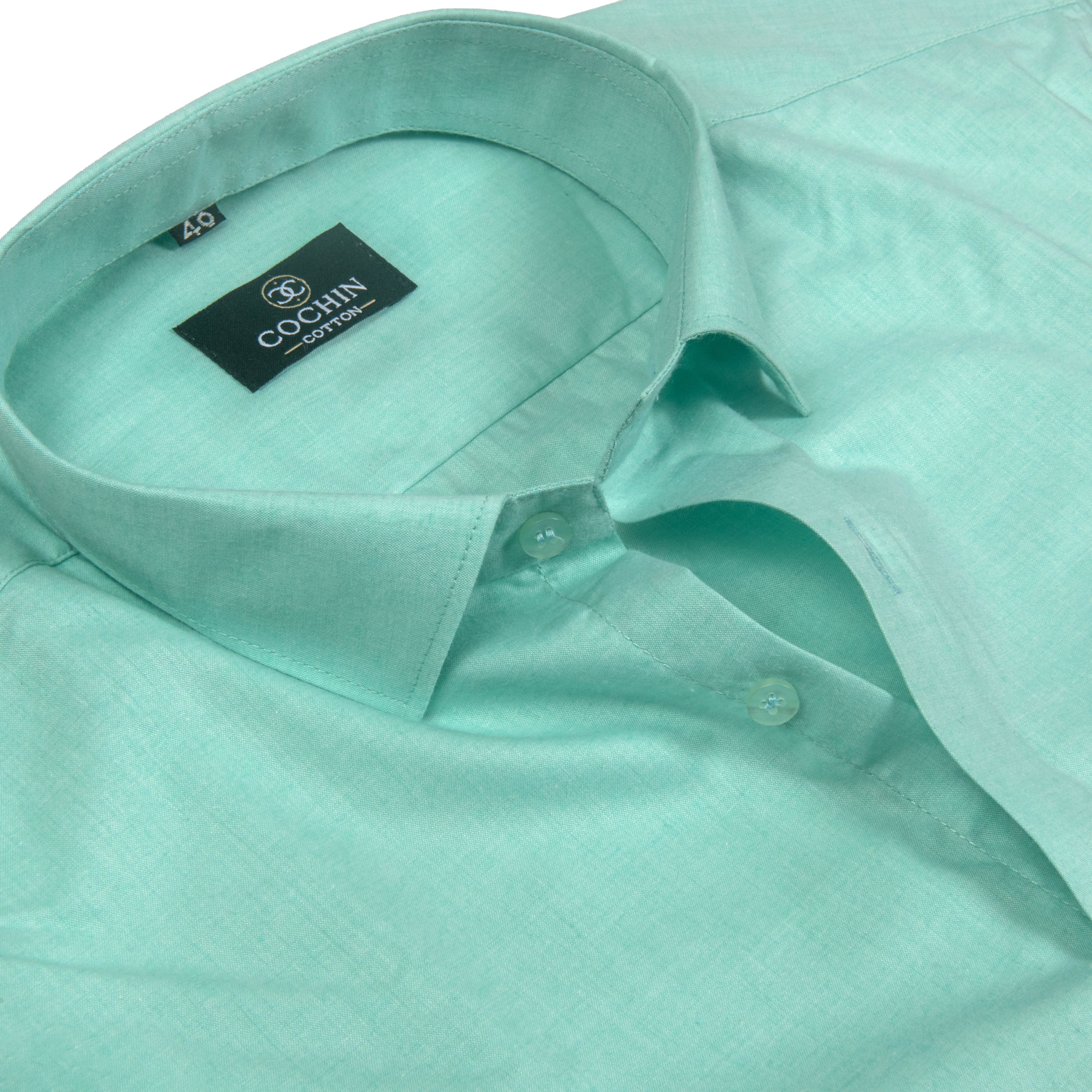A close-up of a mint green dress shirt by COCHAN, showing the collar, inner label, and buttoned placket against a clean white background.