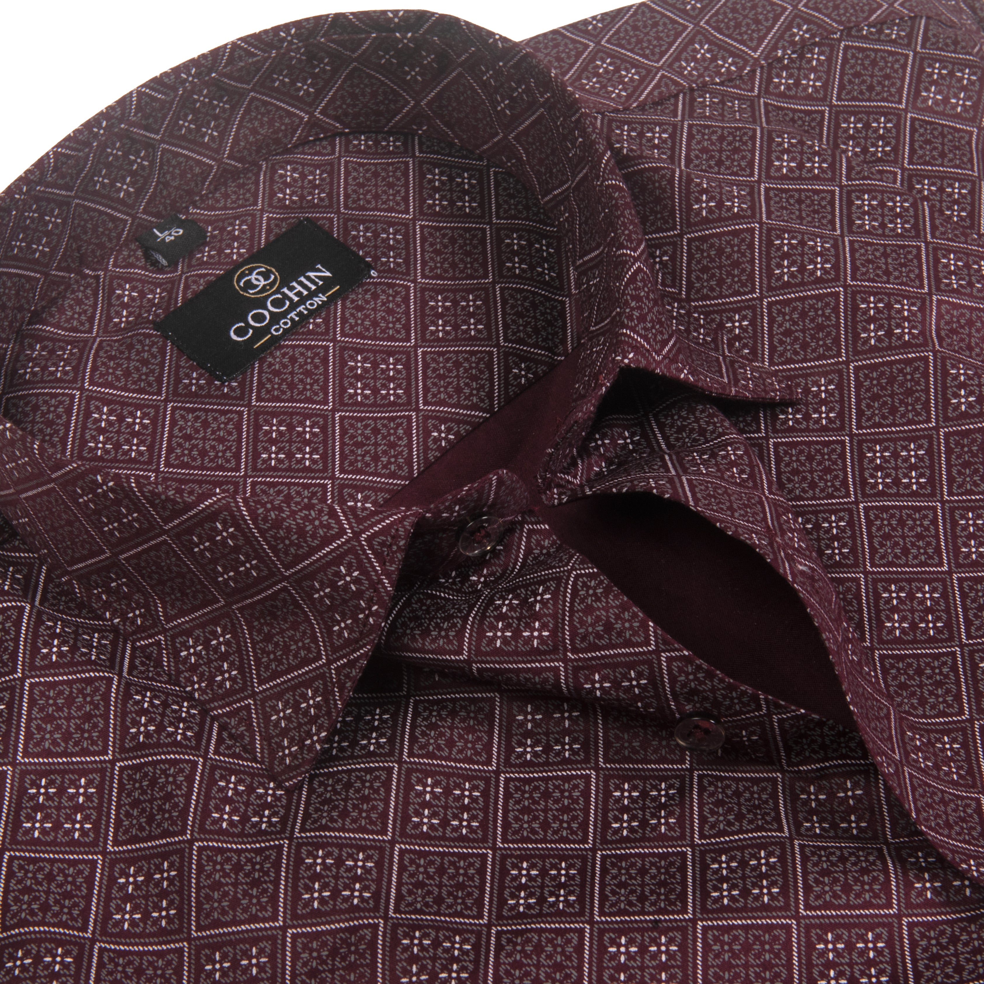 A close-up of a patterned dress shirt collar and inner neck area, showing a black brand label that reads COCHIN CLOTHING. The fabric has a dark burgundy base with a repeating small white geometric grid pattern.