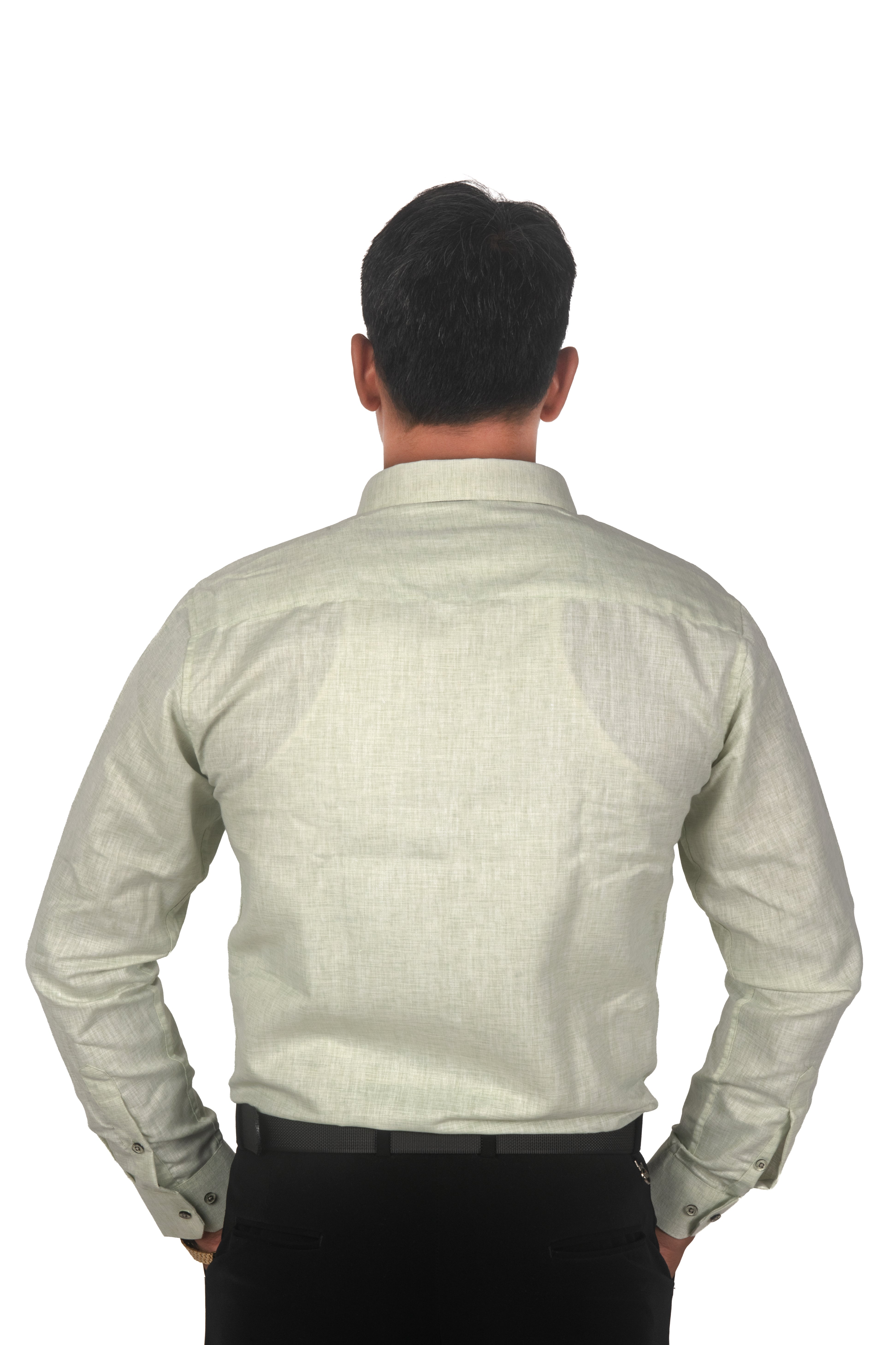 A man viewed from the back wearing a light sage green linen button-down shirt and black trousers, set against a plain white background.