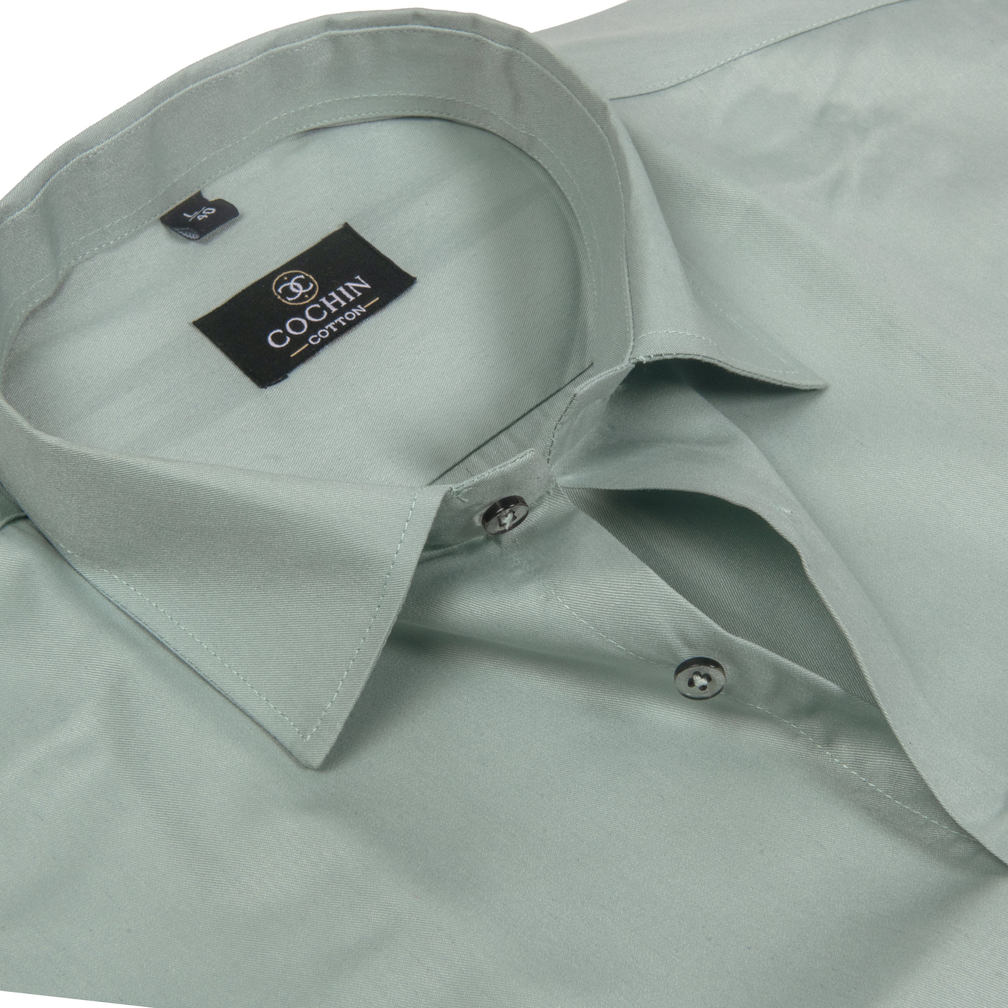 A close-up of a light sage green Cochin cotton dress shirt showing the collar, inner neck label, and button details.