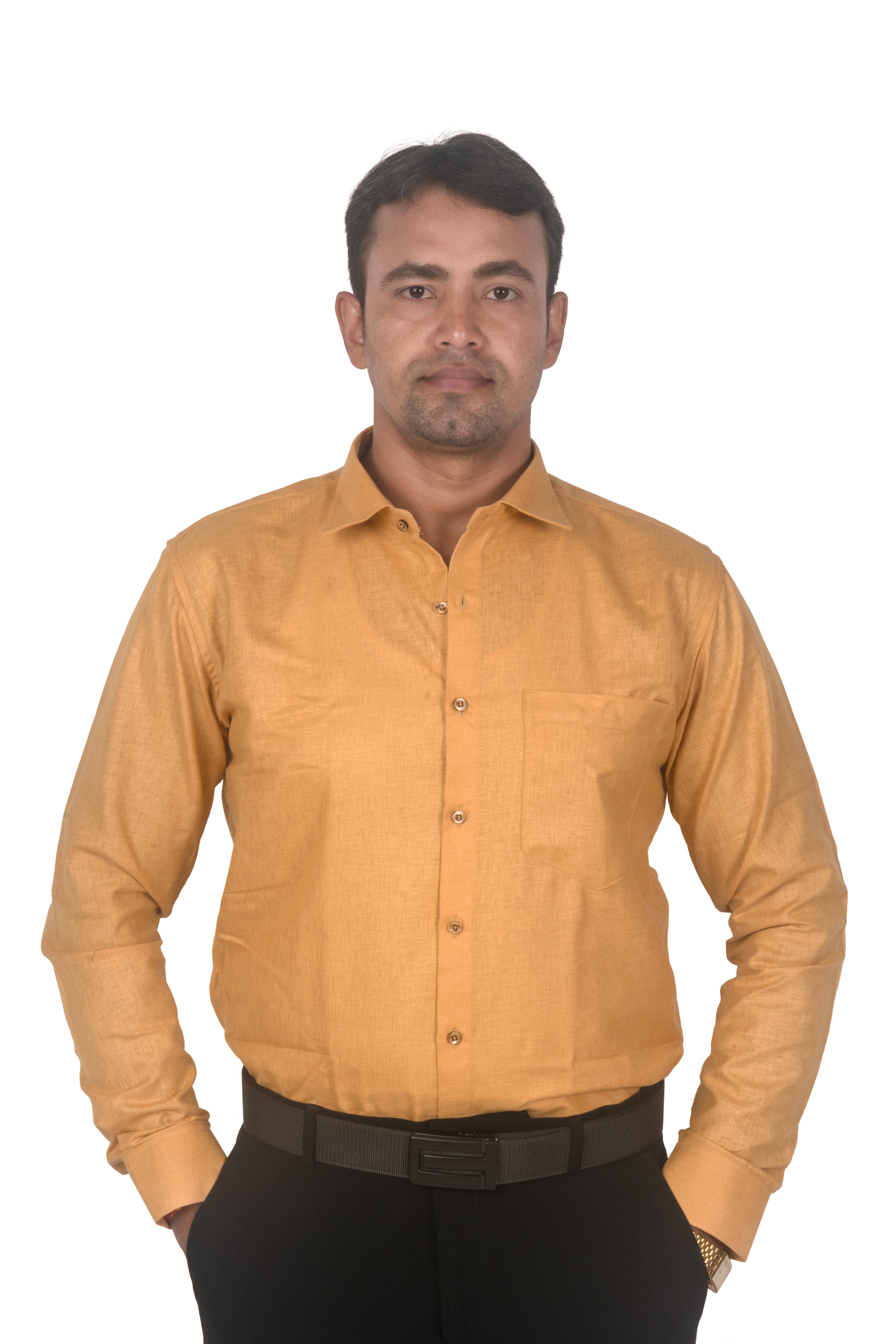 A man wearing a mustard yellow long-sleeve button-down shirt and black trousers, standing against a plain white background.