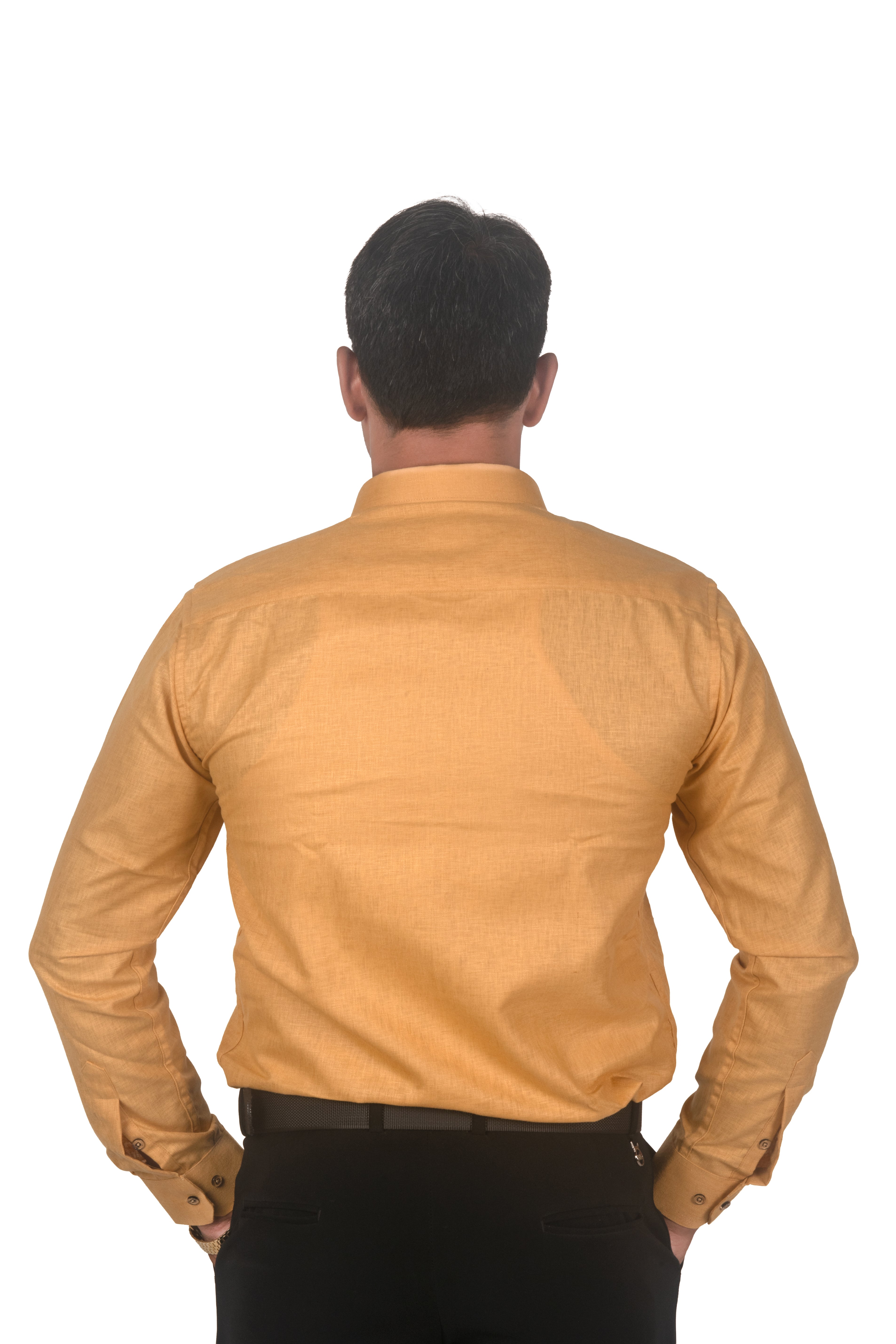 A man viewed from behind wearing a mustard yellow long-sleeve button-up shirt and black trousers, standing against a plain white background.