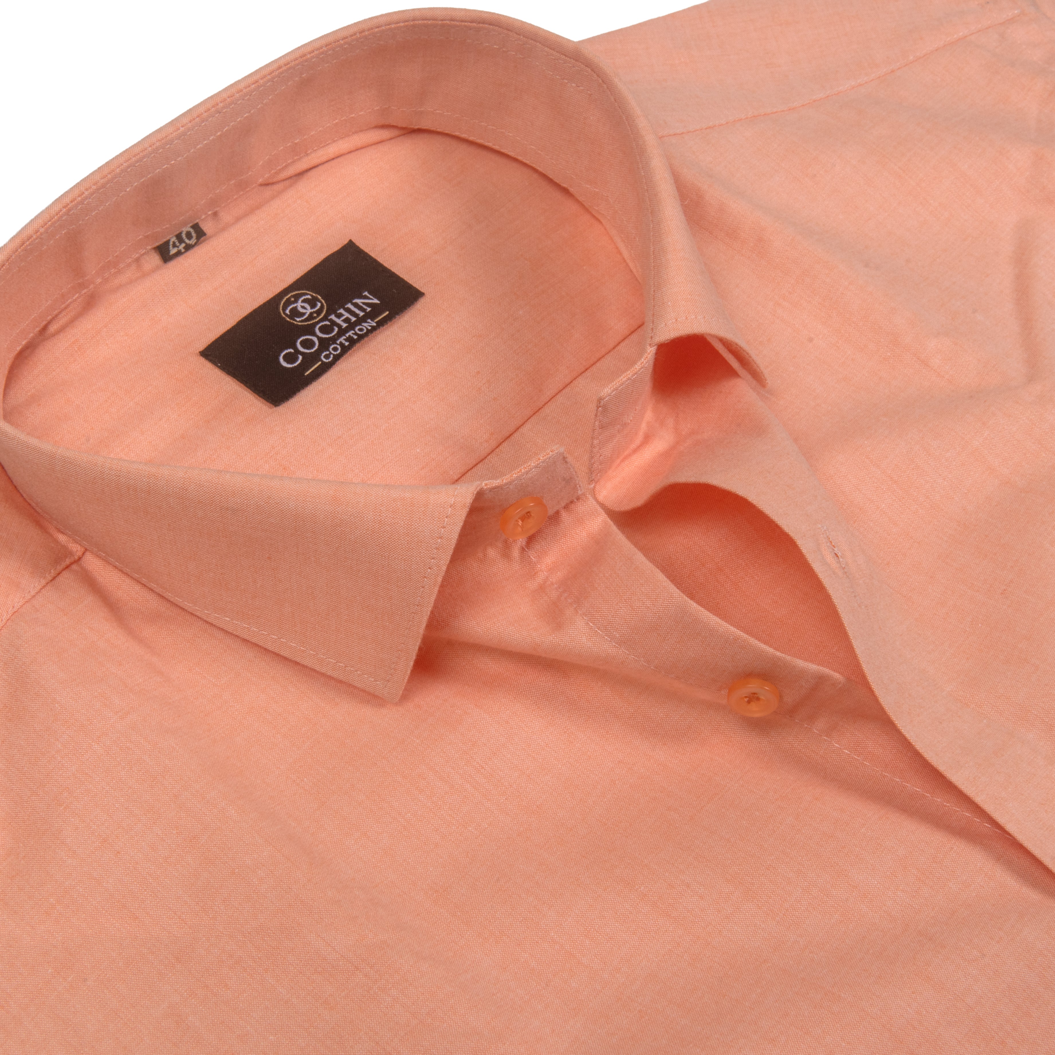 A close-up of a peach-colored long-sleeve dress shirt by Cochin Couture, showing the collar, buttoned placket, and textured fabric.