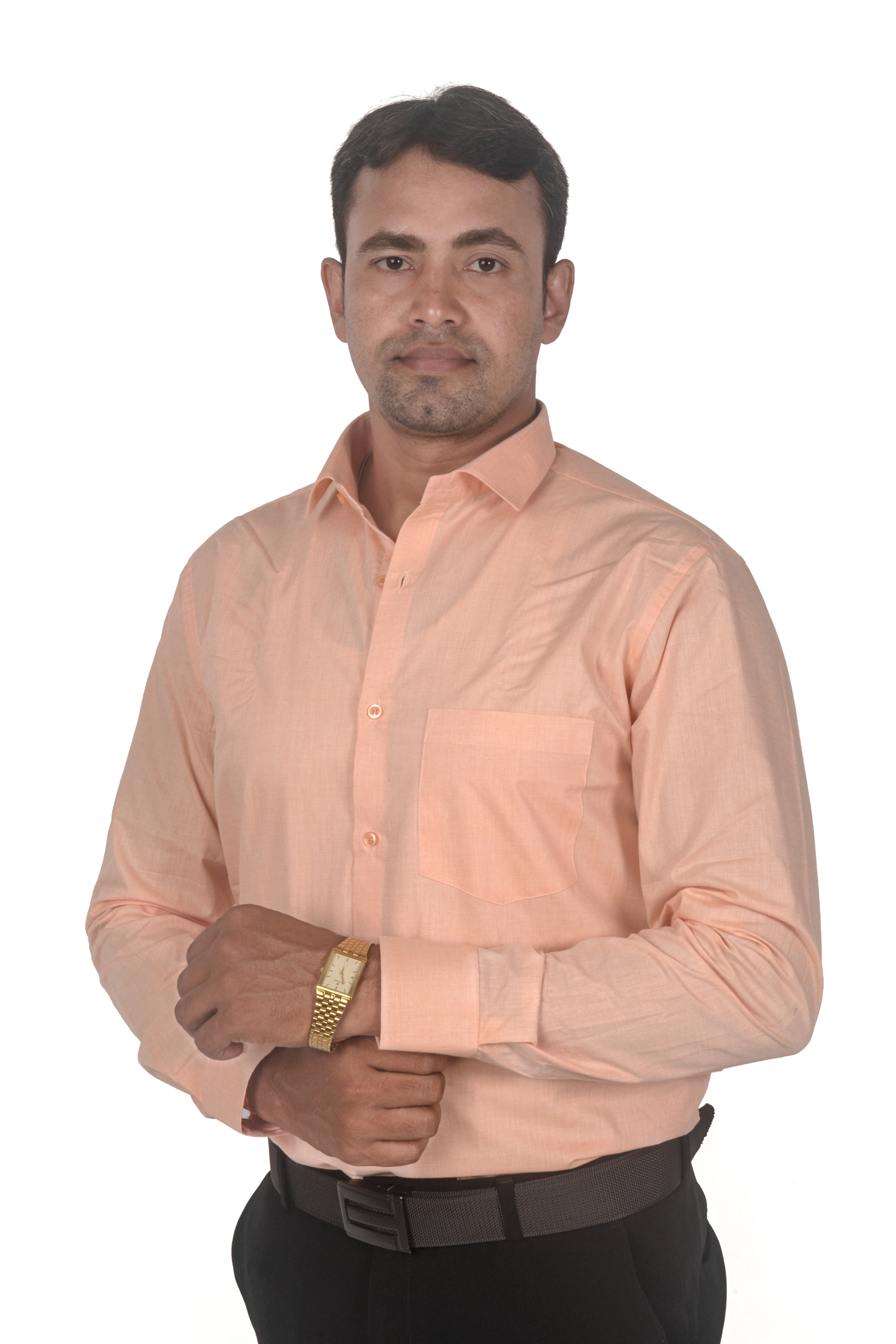 A man wearing a light peach-colored long-sleeve button-down shirt, black trousers, and a gold watch, standing against a plain white background.