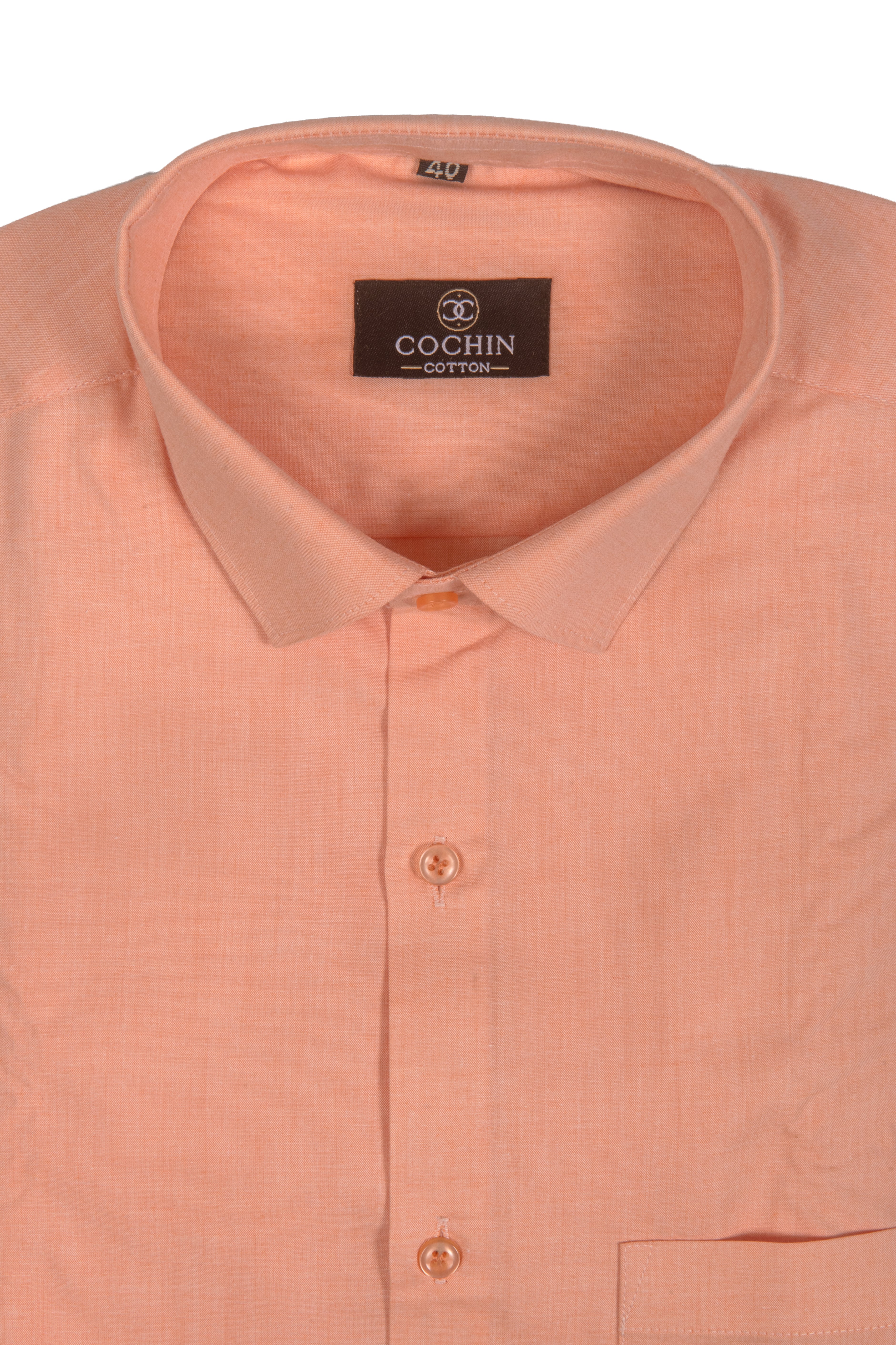 A close-up of a peach-colored Cochin cotton dress shirt showing the collar, inner label, and front buttons against a white background.