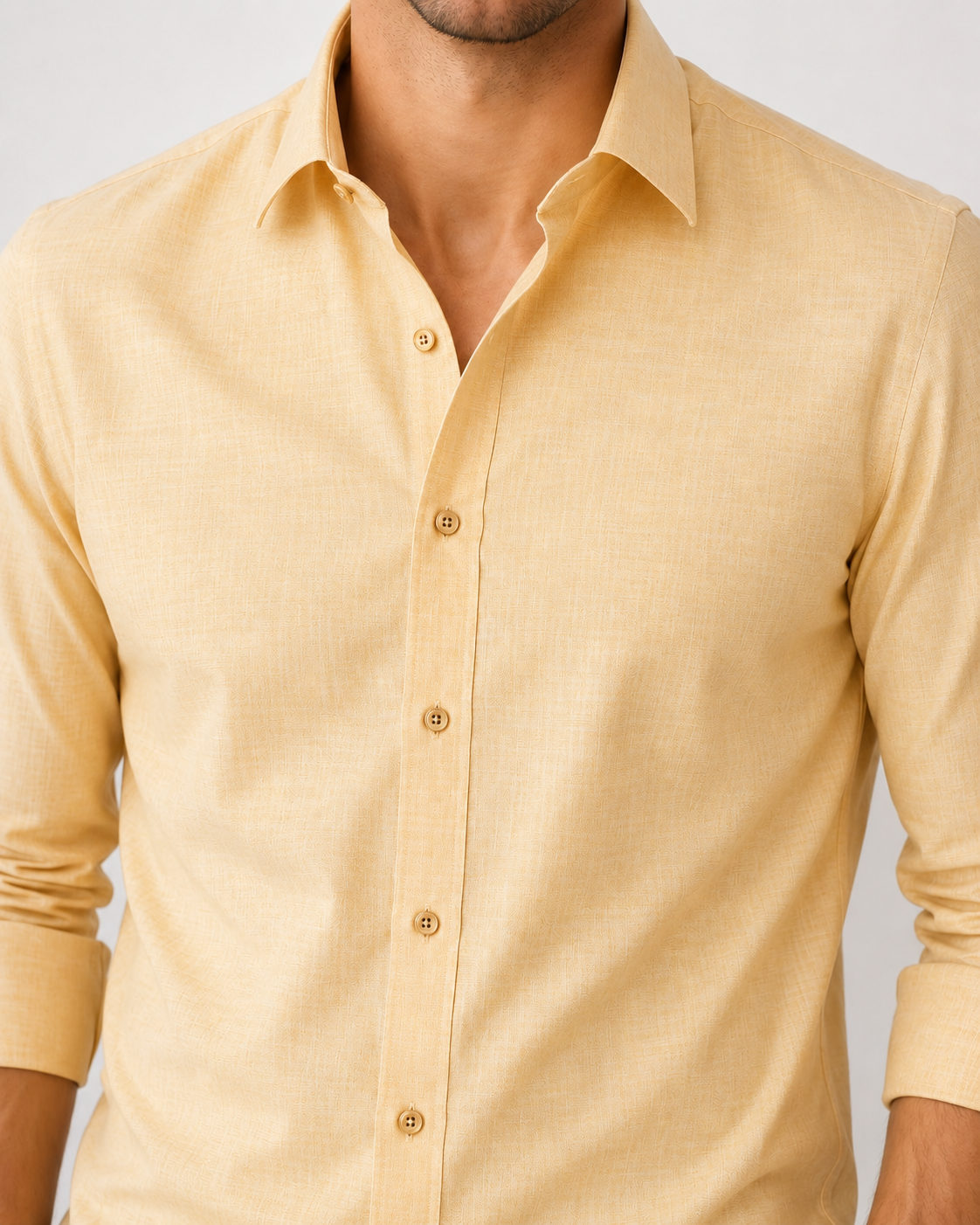 Beige button-up shirt worn by a person on a light gray background
