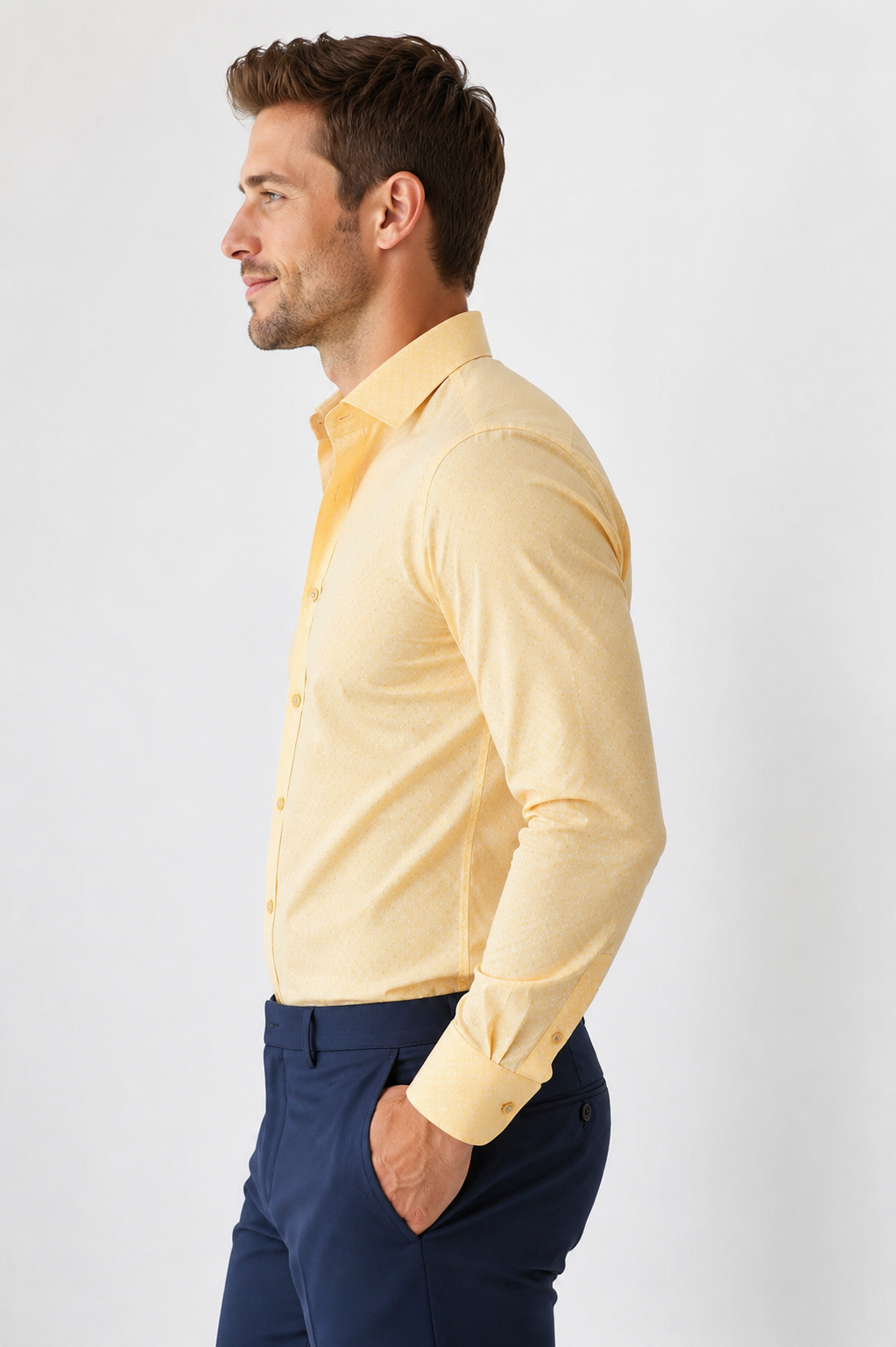 Man wearing a light yellow shirt and dark blue pants on a white background