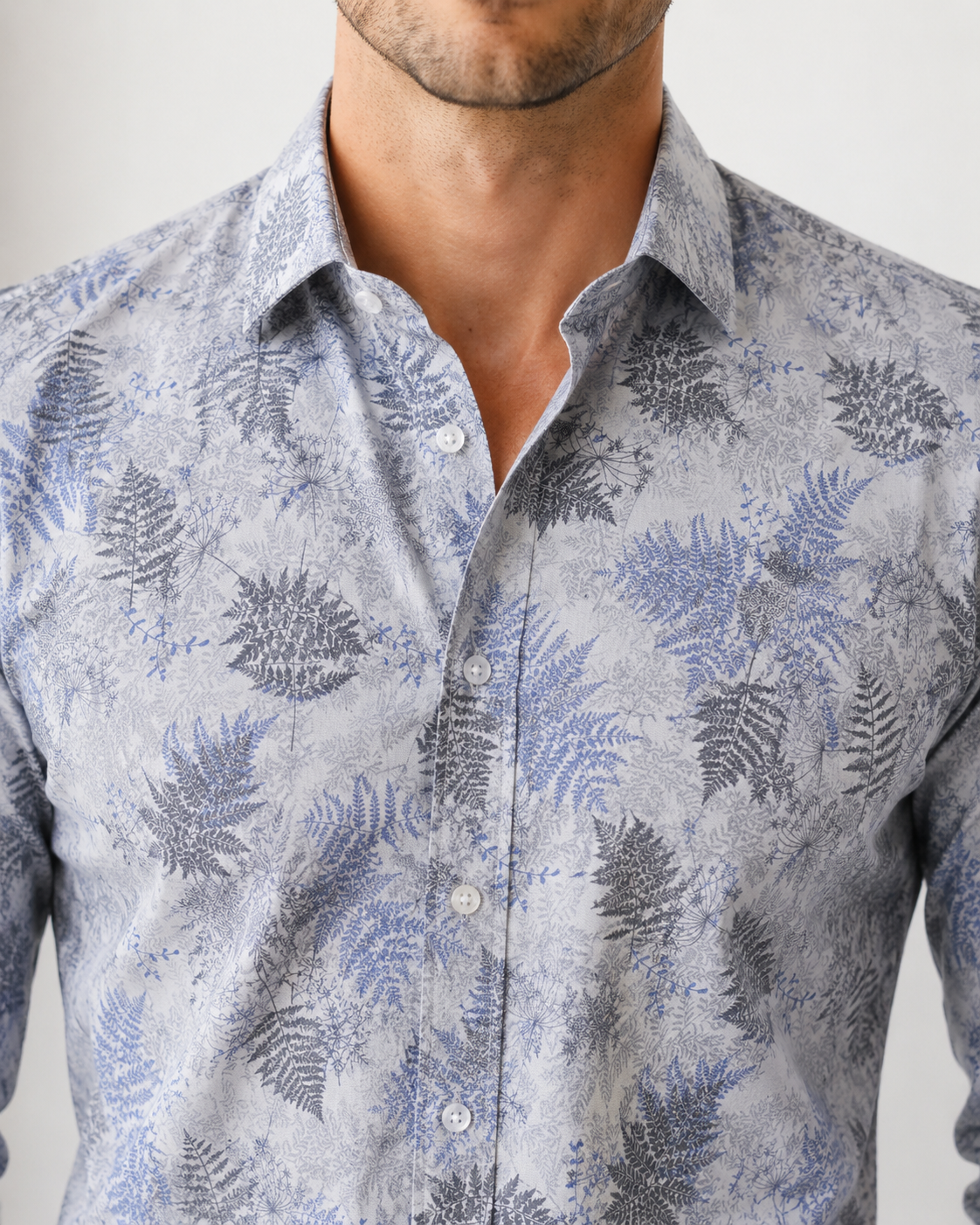 Man wearing a patterned shirt with fern design on a plain background