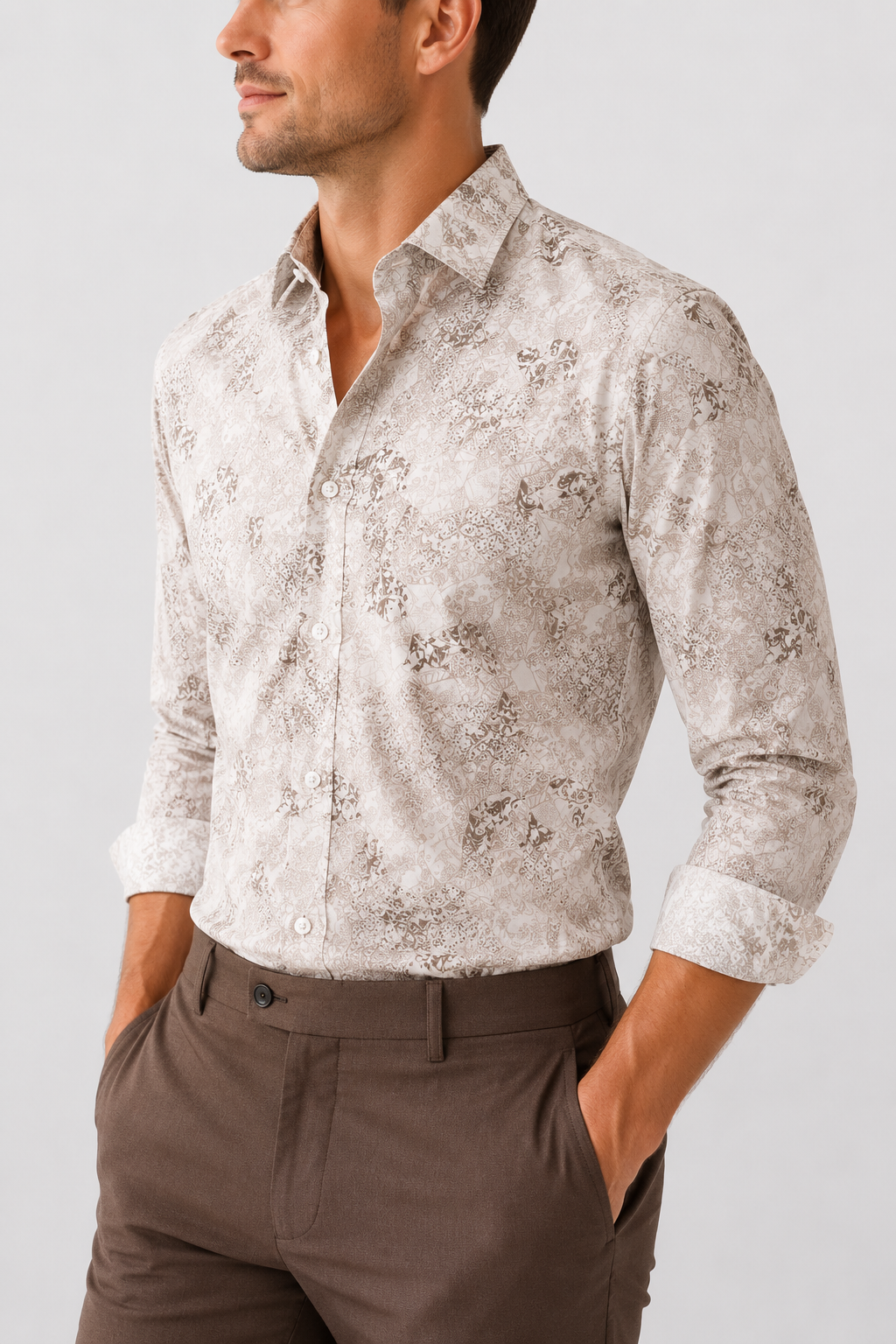Man wearing a patterned shirt and brown pants on a plain background