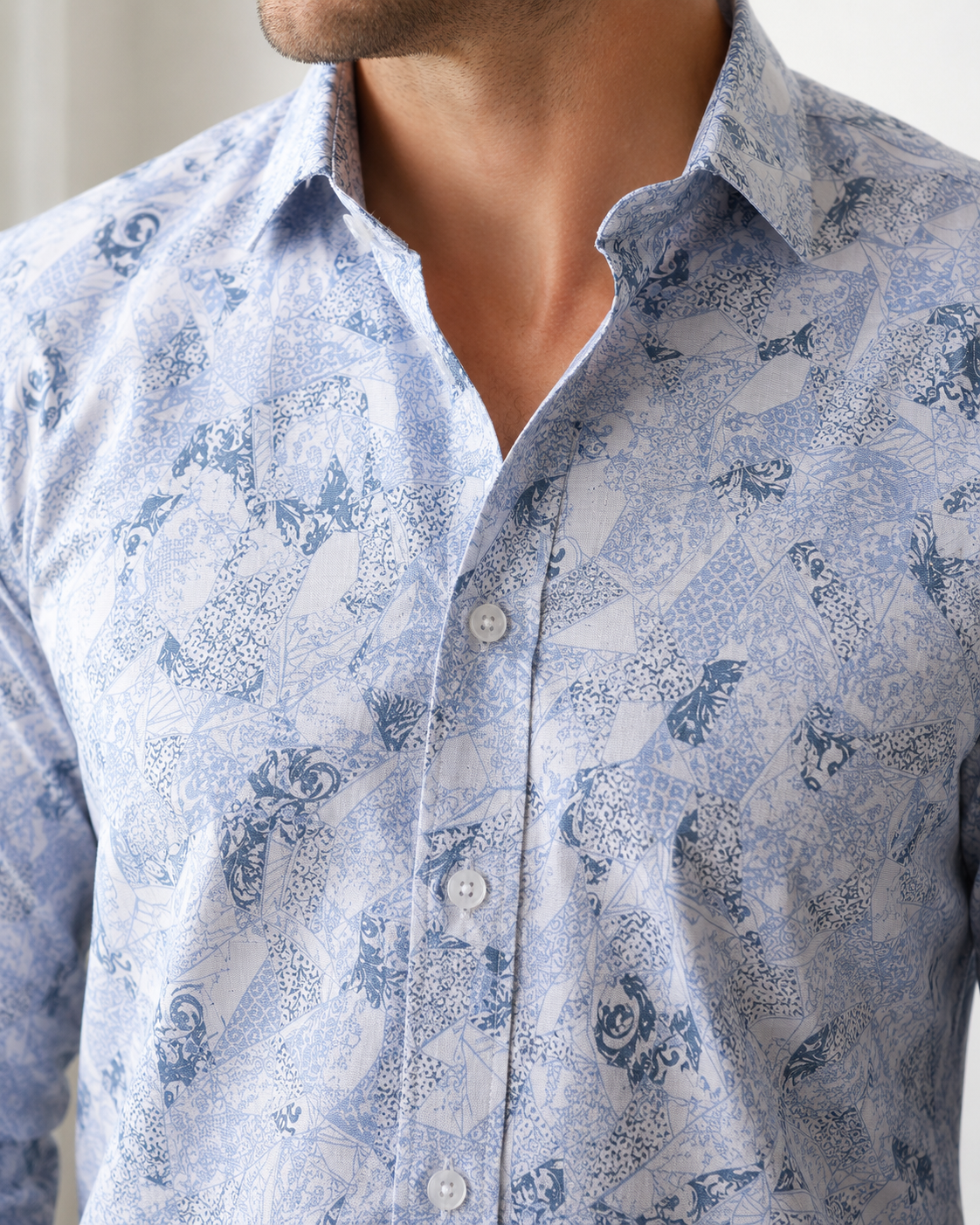 Close-up of a man wearing a blue patterned shirt with a neutral background