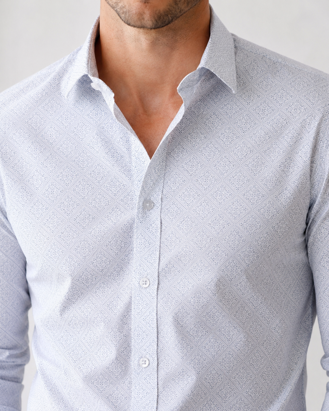 Man wearing a light gray patterned shirt against a plain background