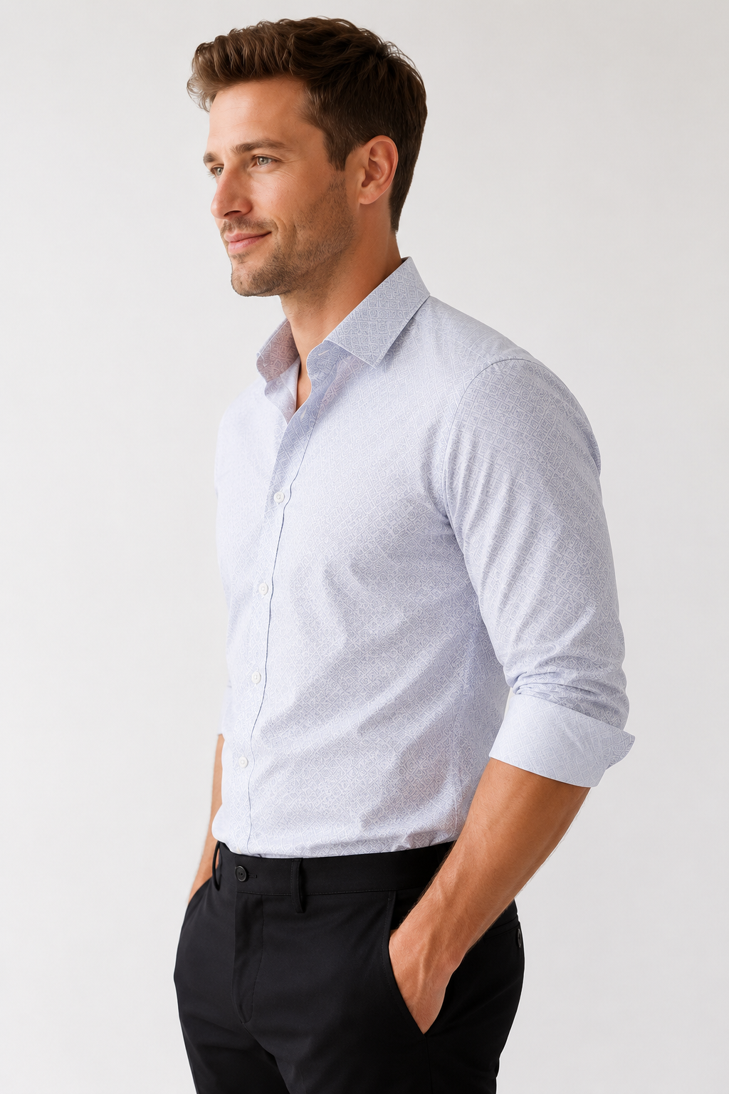 Man wearing a light gray button-up shirt with rolled-up sleeves and black pants on a white background
