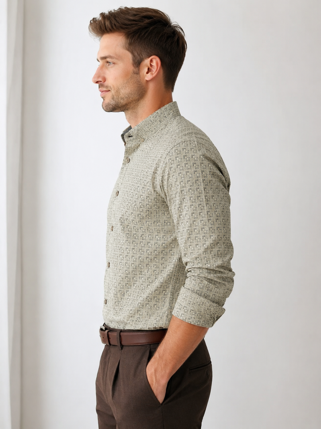 Man wearing a patterned shirt and brown pants against a white background