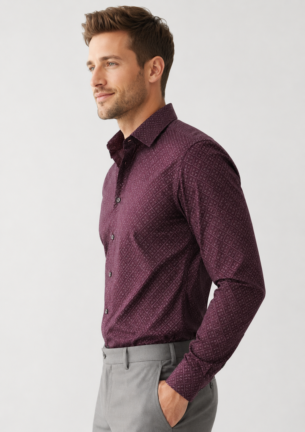 Man wearing a patterned purple shirt and gray pants on a light gray background
