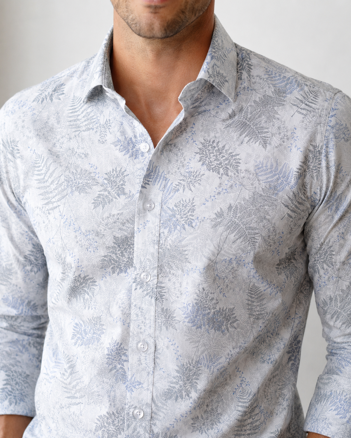 Man wearing a light gray patterned shirt against a neutral background