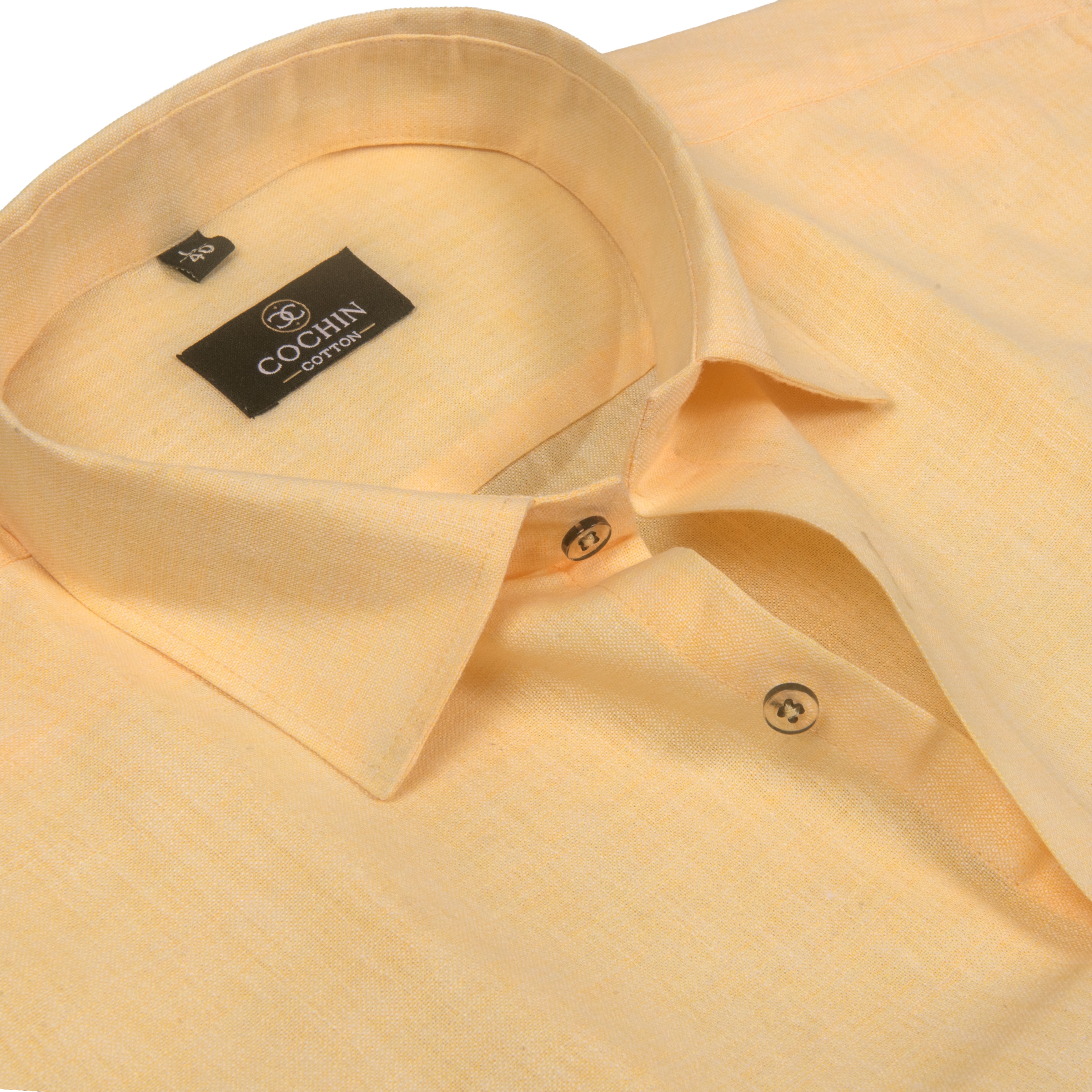 A close-up of a light peach-beige linen shirt by COGNIN, showing the collar, buttoned placket, and textured fabric.