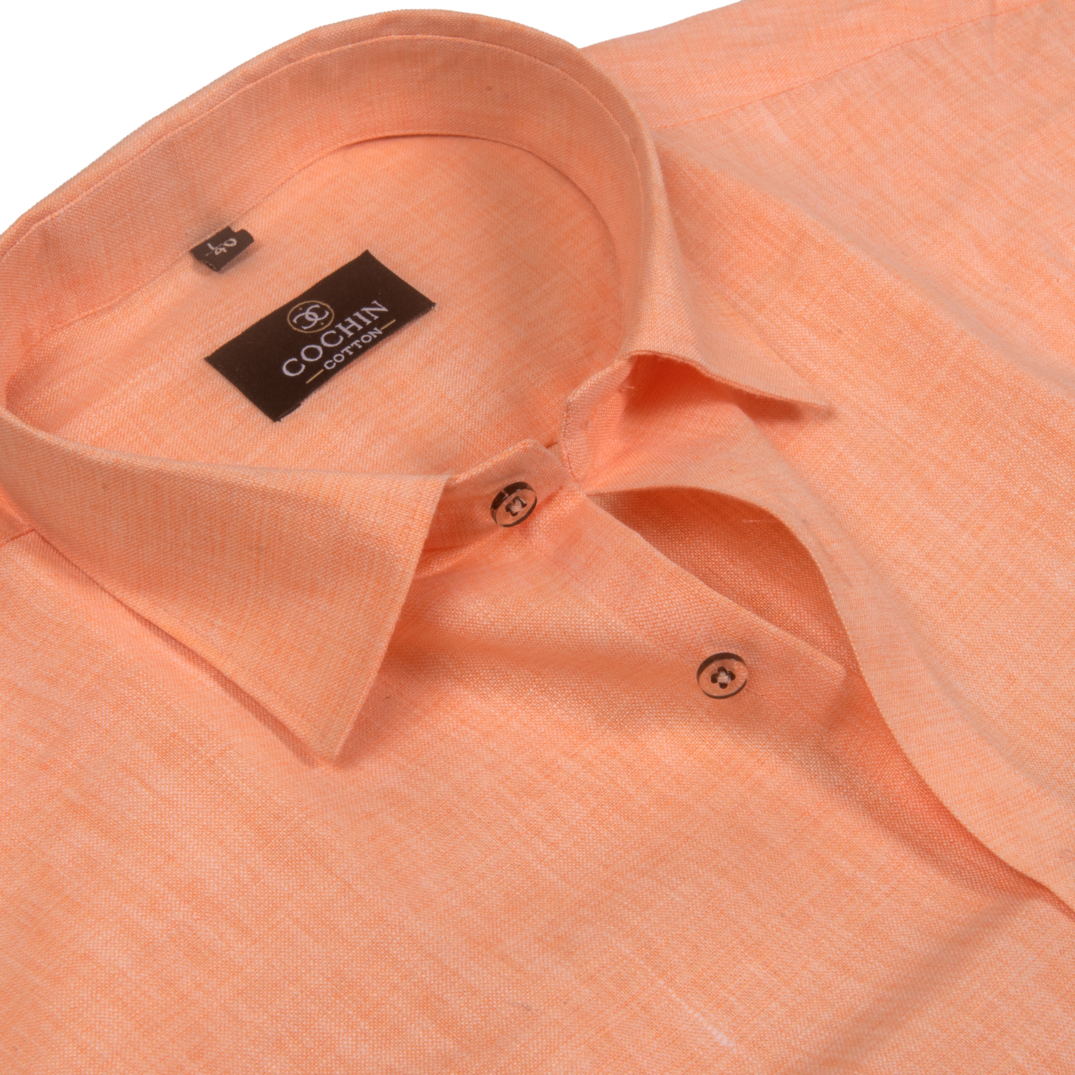 Close-up of a peach-colored linen shirt by Cochin Couture, showing the collar, buttons, and textured fabric.