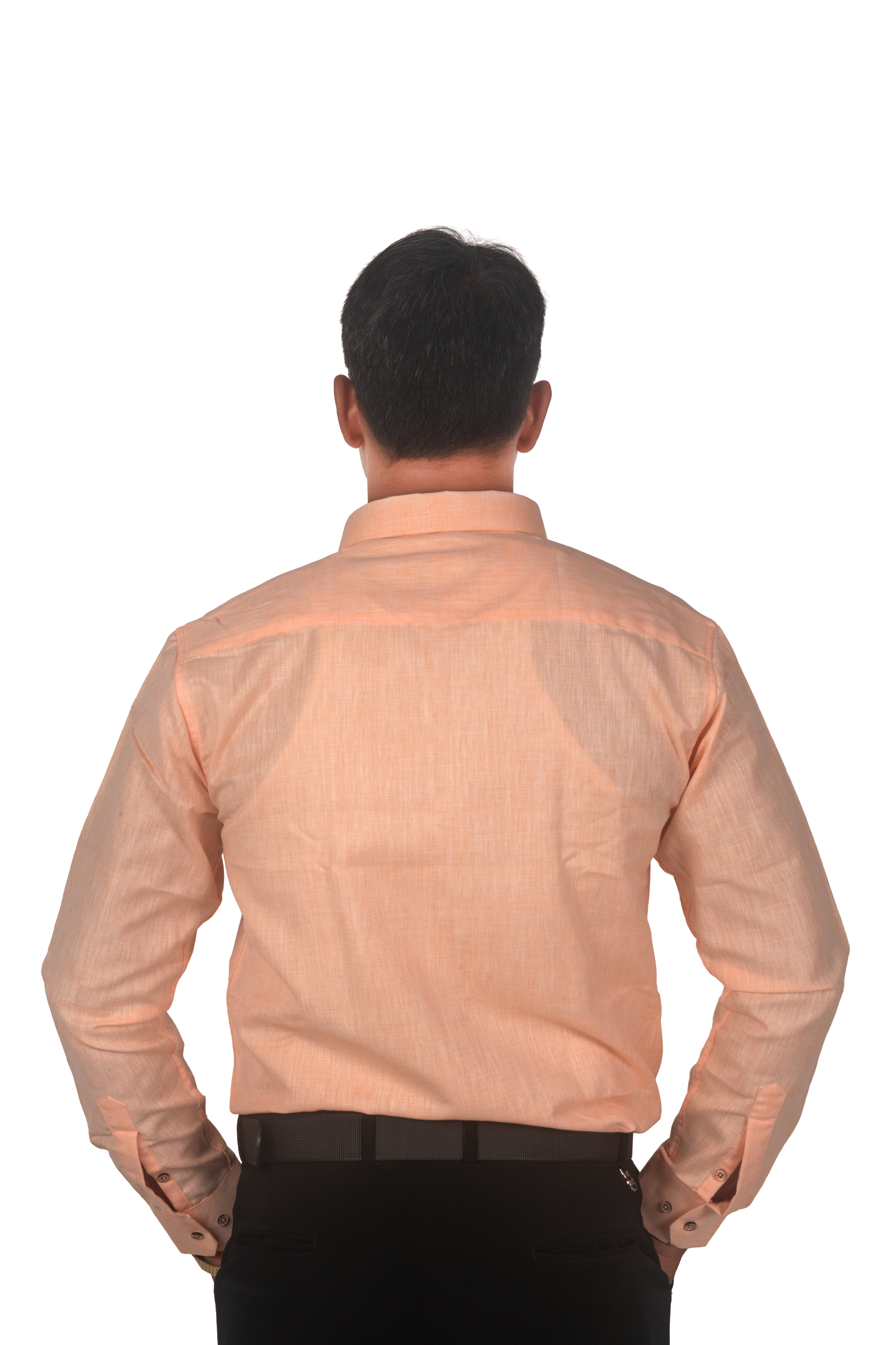 A man viewed from behind wearing a light peach-colored long-sleeve linen shirt and black trousers, standing against a solid white background.