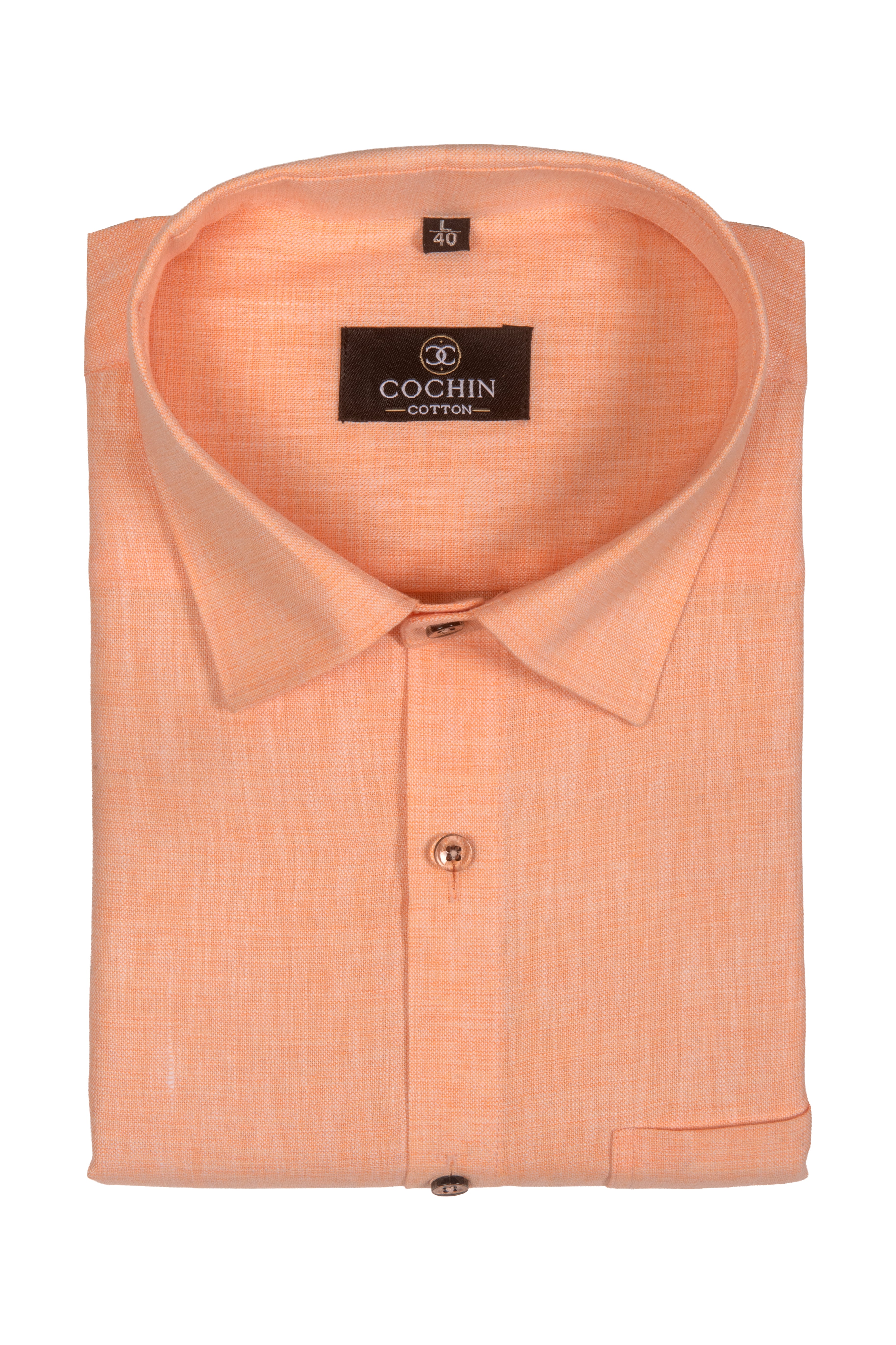 A folded peach-colored long-sleeve dress shirt with a textured weave, featuring a pointed collar, a button-down front, and a black brand label reading 'COCHIN COTTON'.