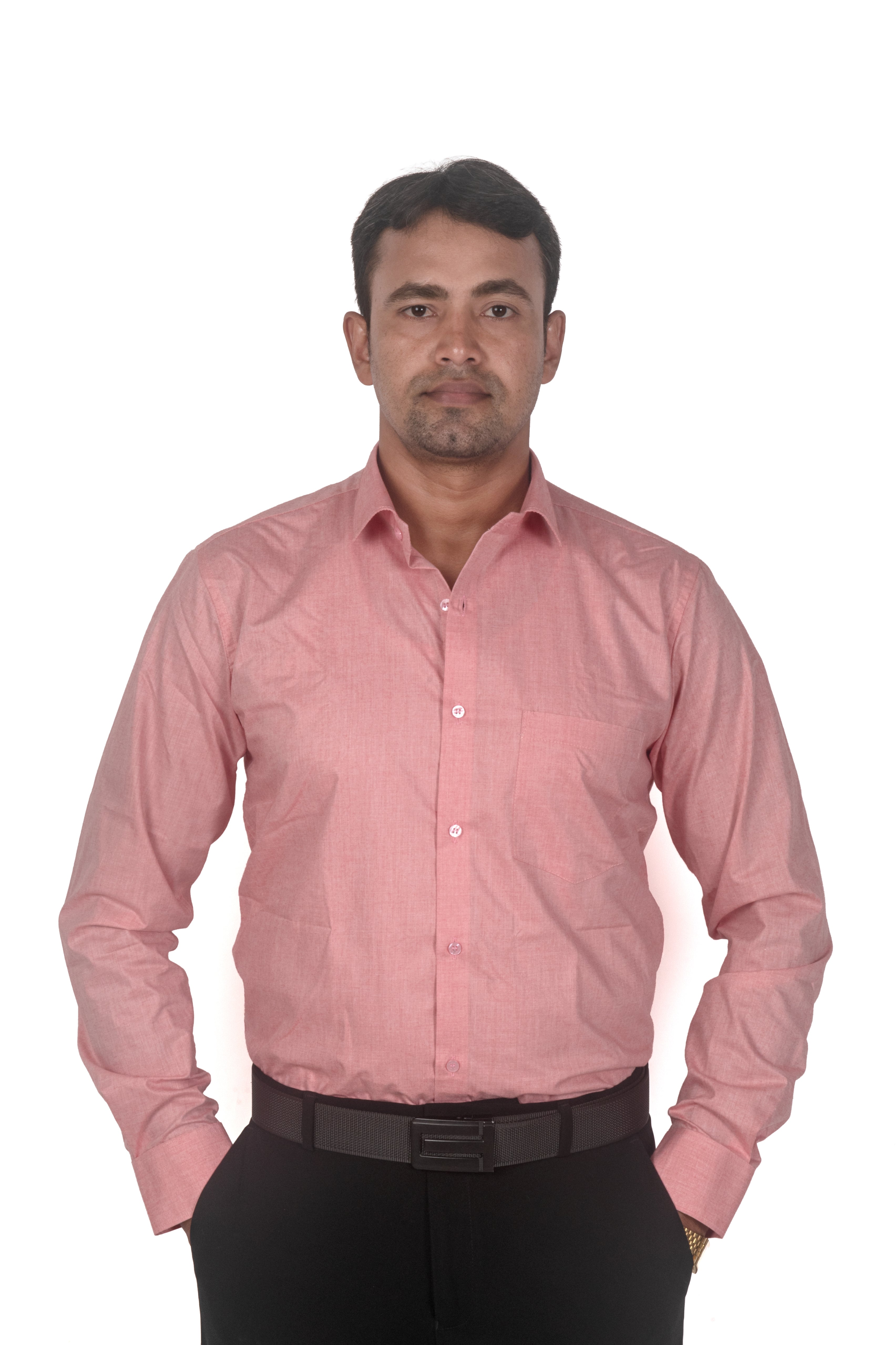 A man wearing a light pink long-sleeve button-down shirt and black trousers, standing against a plain white background.