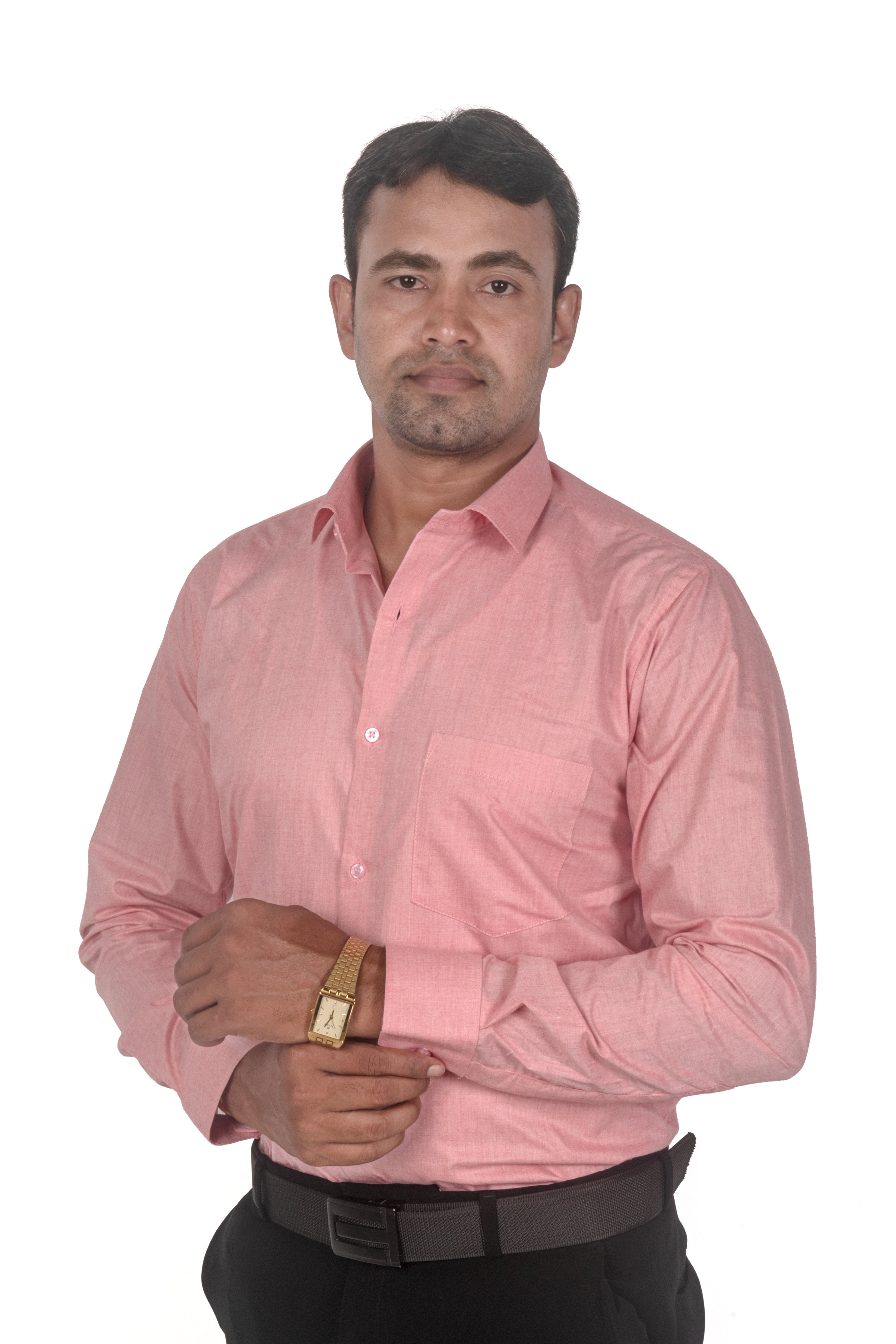 A man wearing a light pink long-sleeve button-down shirt, black trousers, and a brown belt, standing against a plain white background.
