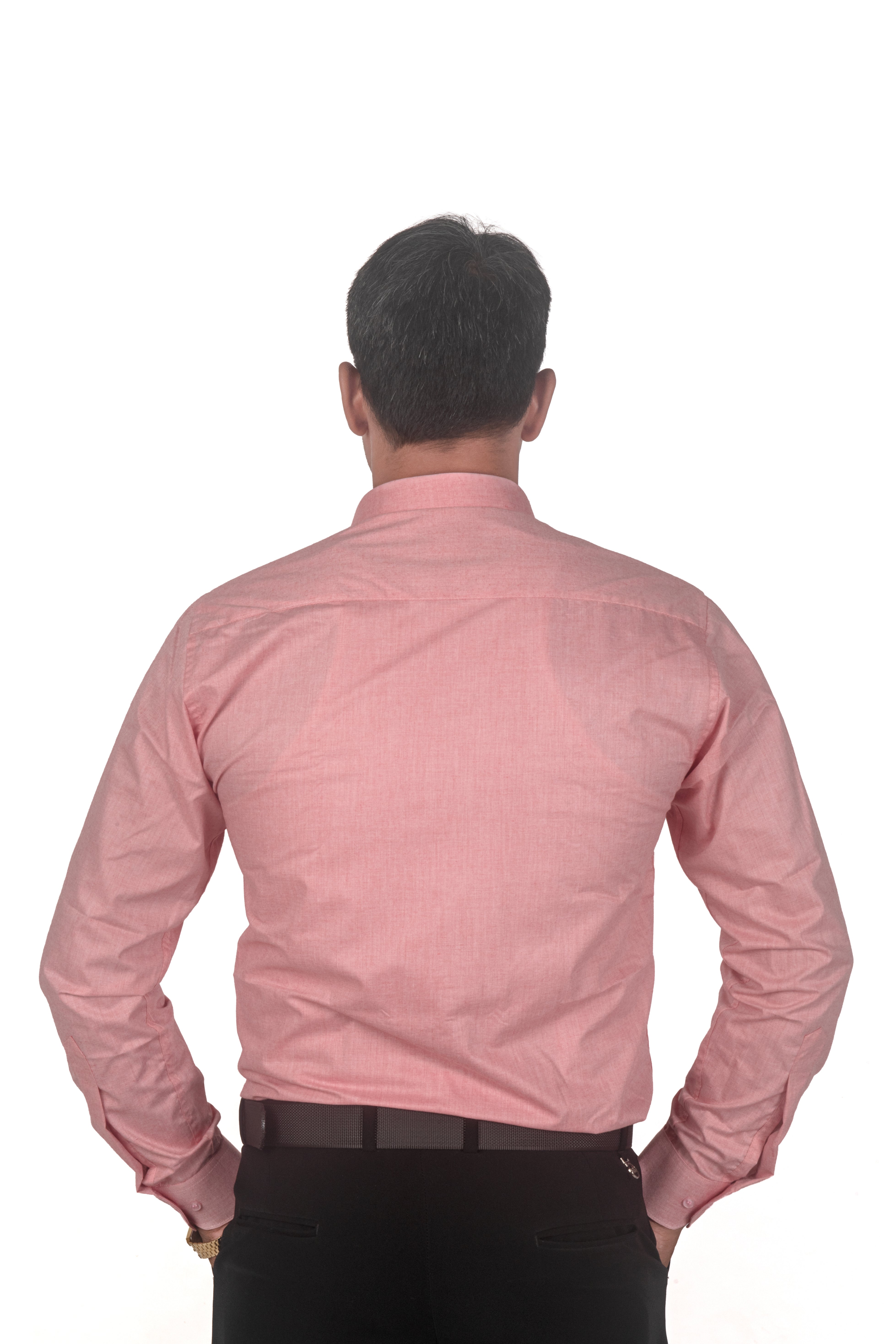 A man viewed from behind wearing a light pink long-sleeve button-down shirt and black trousers, standing against a plain white background.