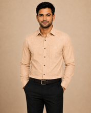 A man wearing a light beige long-sleeve button-down shirt and black trousers, standing against a solid beige background.