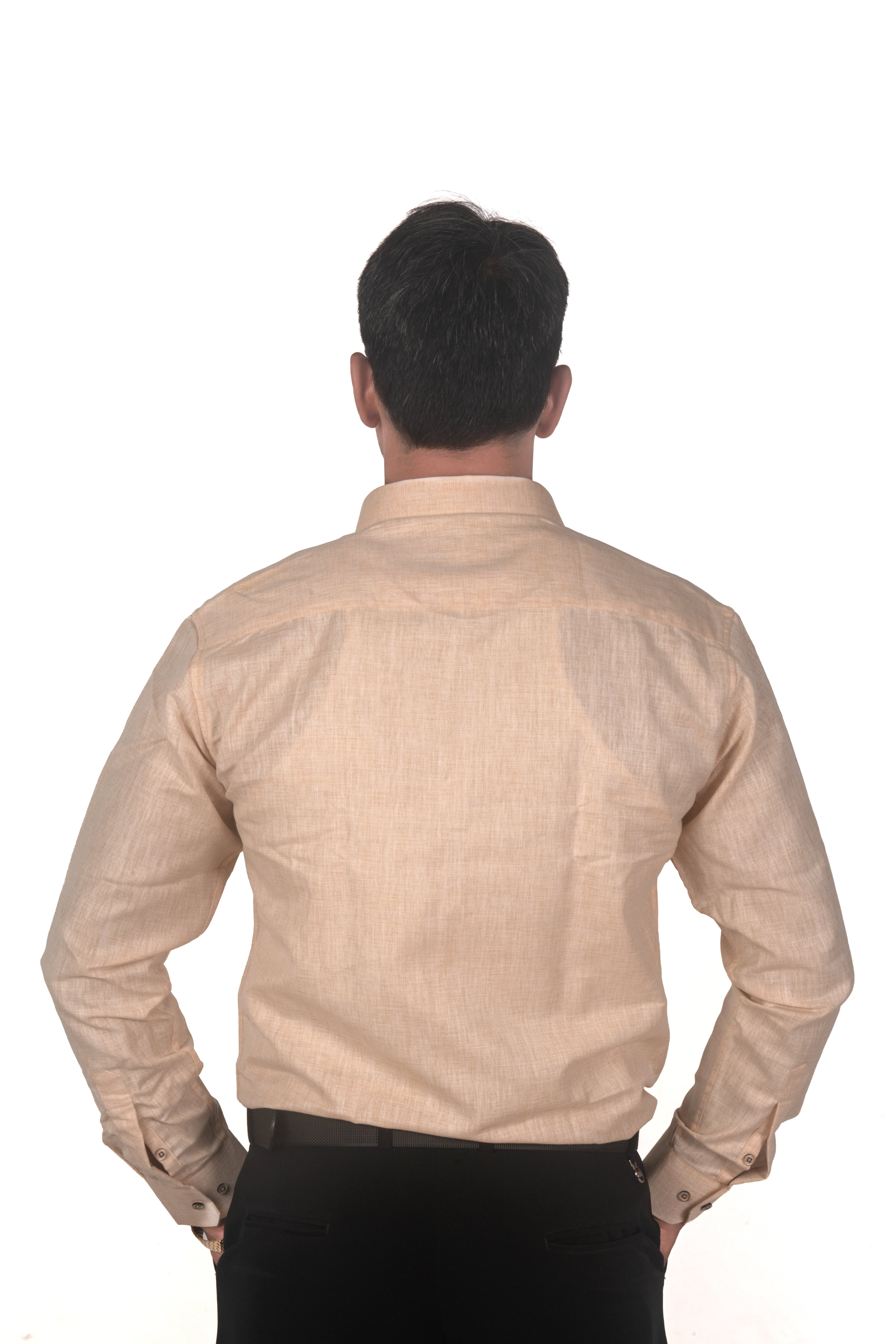 A man viewed from behind wearing a light beige long-sleeve linen shirt and black trousers, standing against a solid white background.