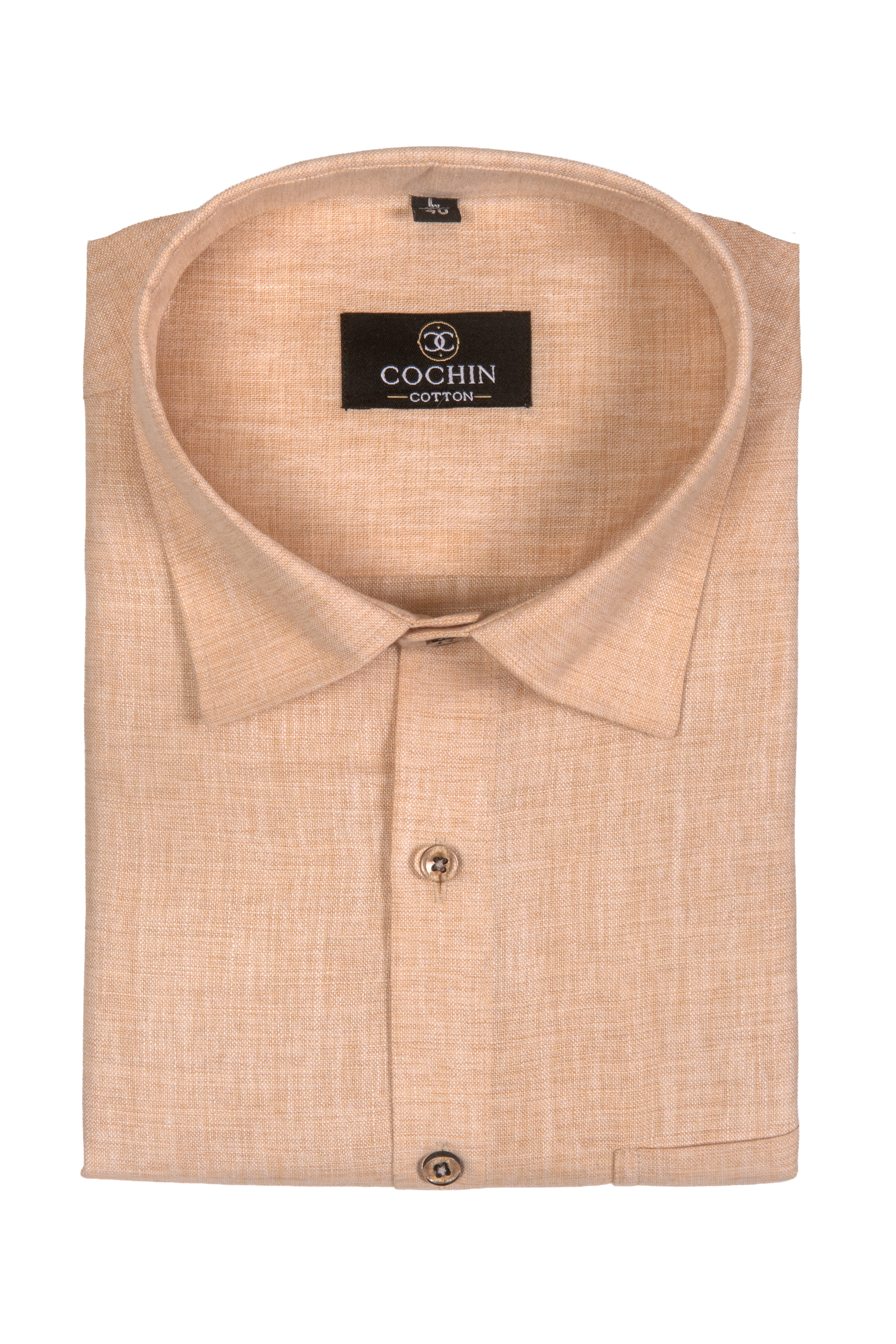 A folded light peach-beige linen shirt with a pointed collar and a black Coghin Cotton brand label inside the collar, set against a plain white background.