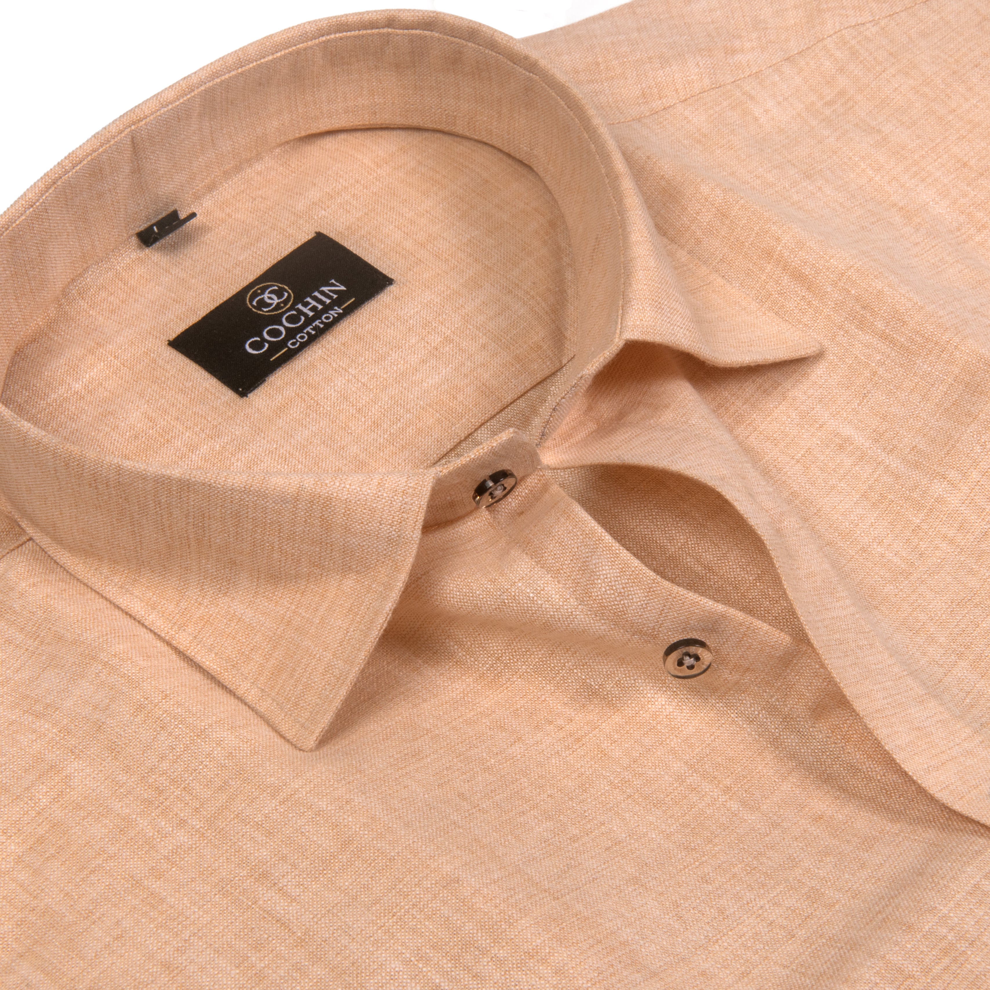 A close-up of a light peach-beige linen shirt by Coccin Collection, showing the collar, brand label, and textured fabric.