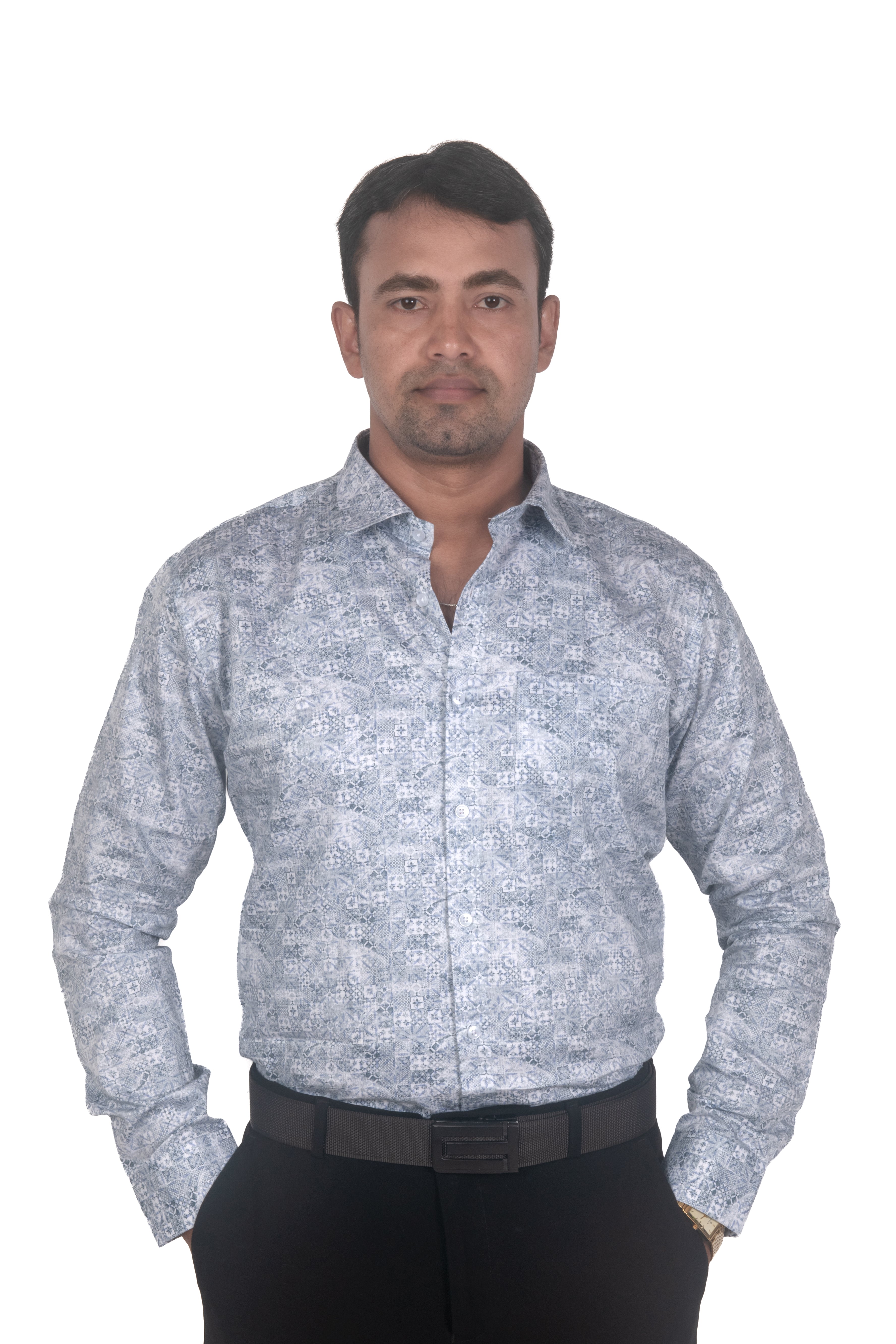 A man wearing a light blue and white patterned long-sleeve button-down shirt with black trousers, standing against a plain white background.