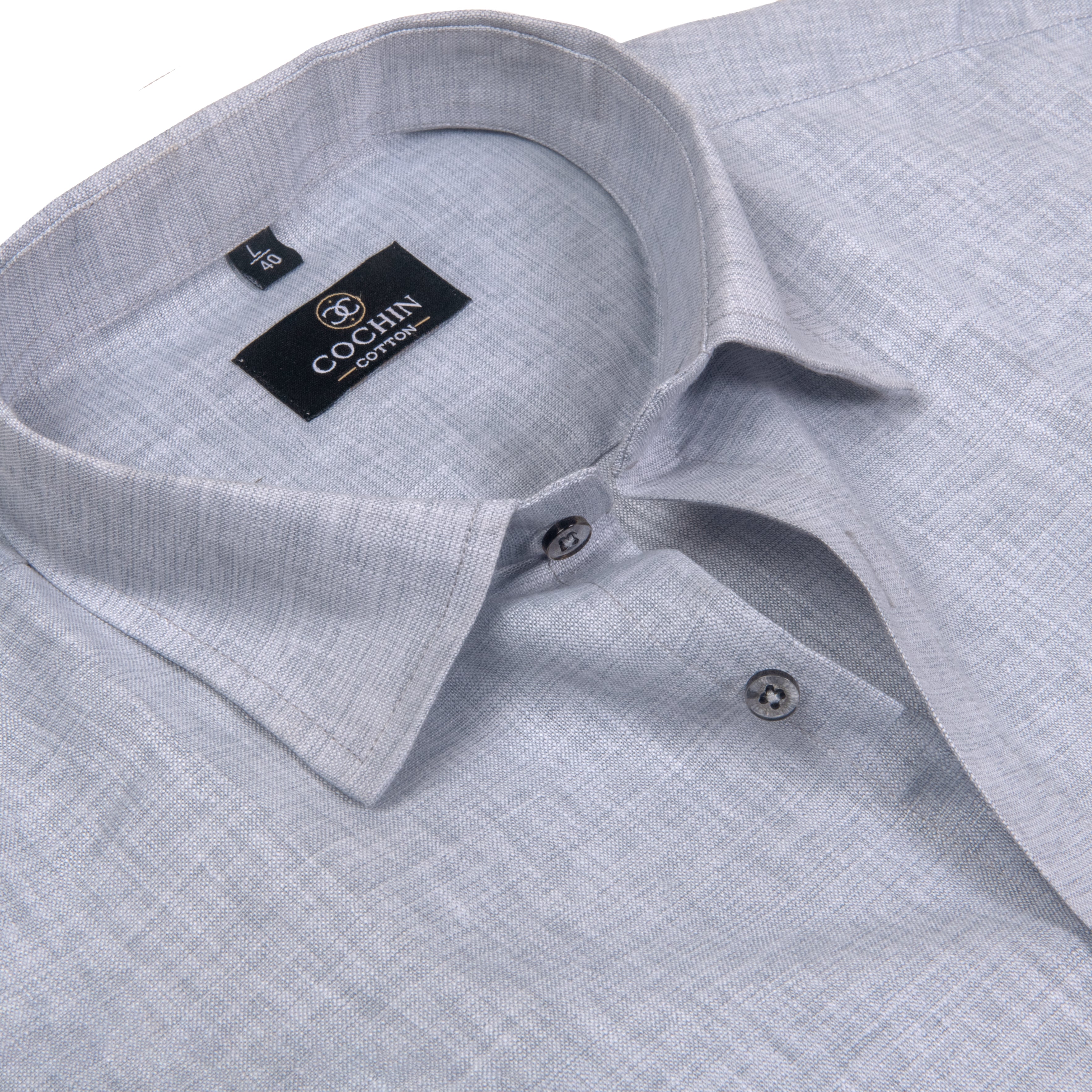 Close-up of a light gray textured linen shirt collar with a black Coghlin brand label inside the neck, showing two silver buttons.