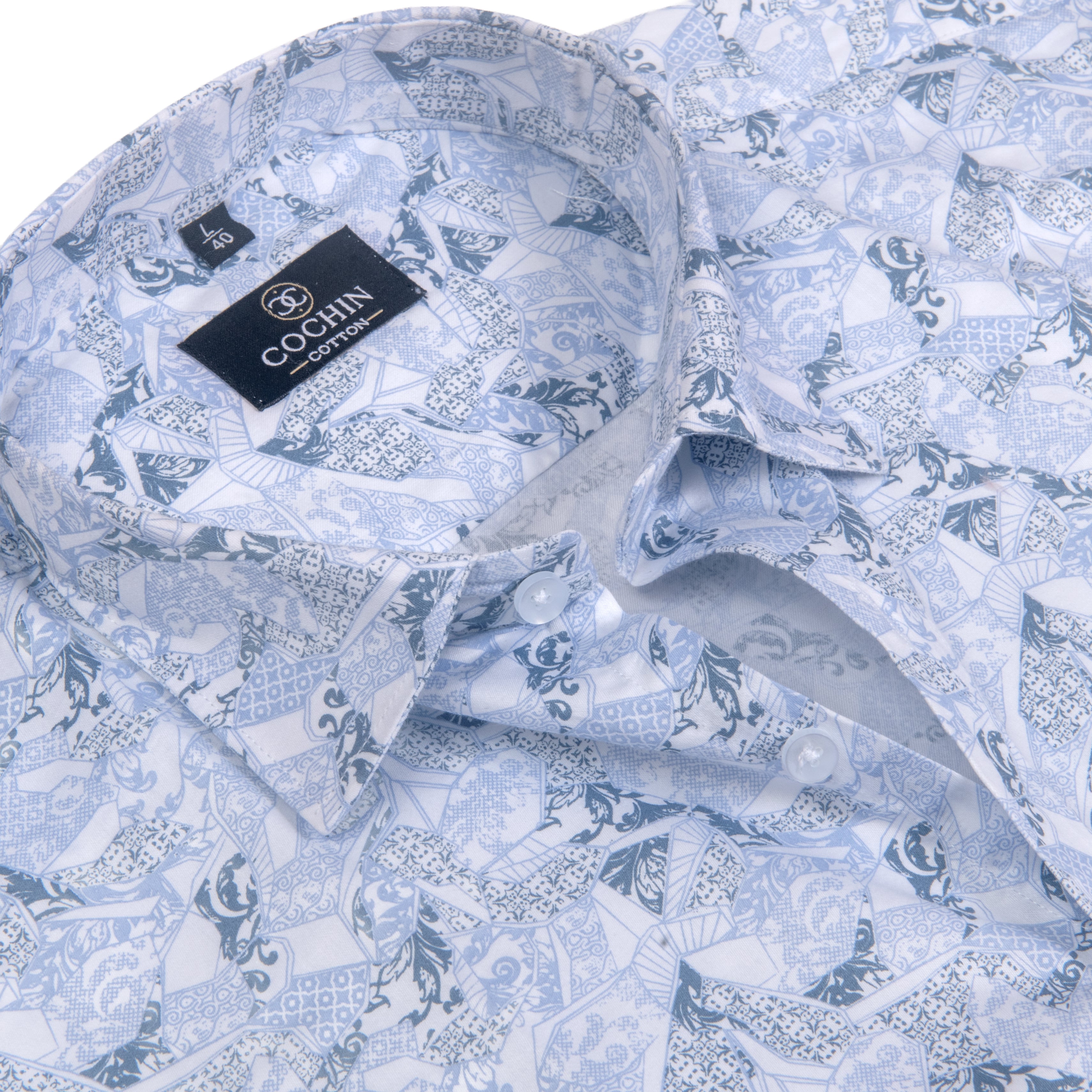 A close-up of a light blue and white patterned button-down shirt by Cohlin, featuring a detailed blue graphic print and a black brand label on the collar.