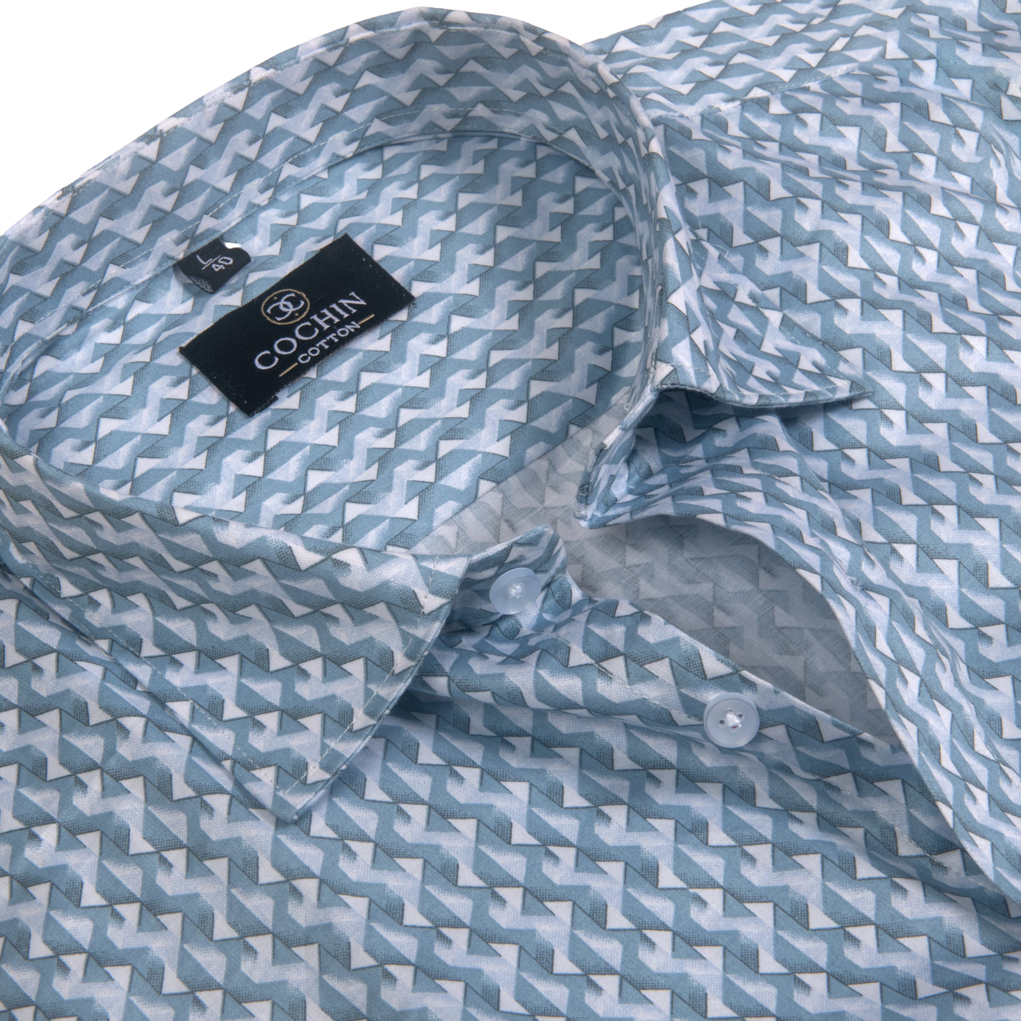 A close-up of a Cochin Crystal men's dress shirt featuring a geometric zigzag pattern in light blue and white, with a black brand label visible inside the collar.