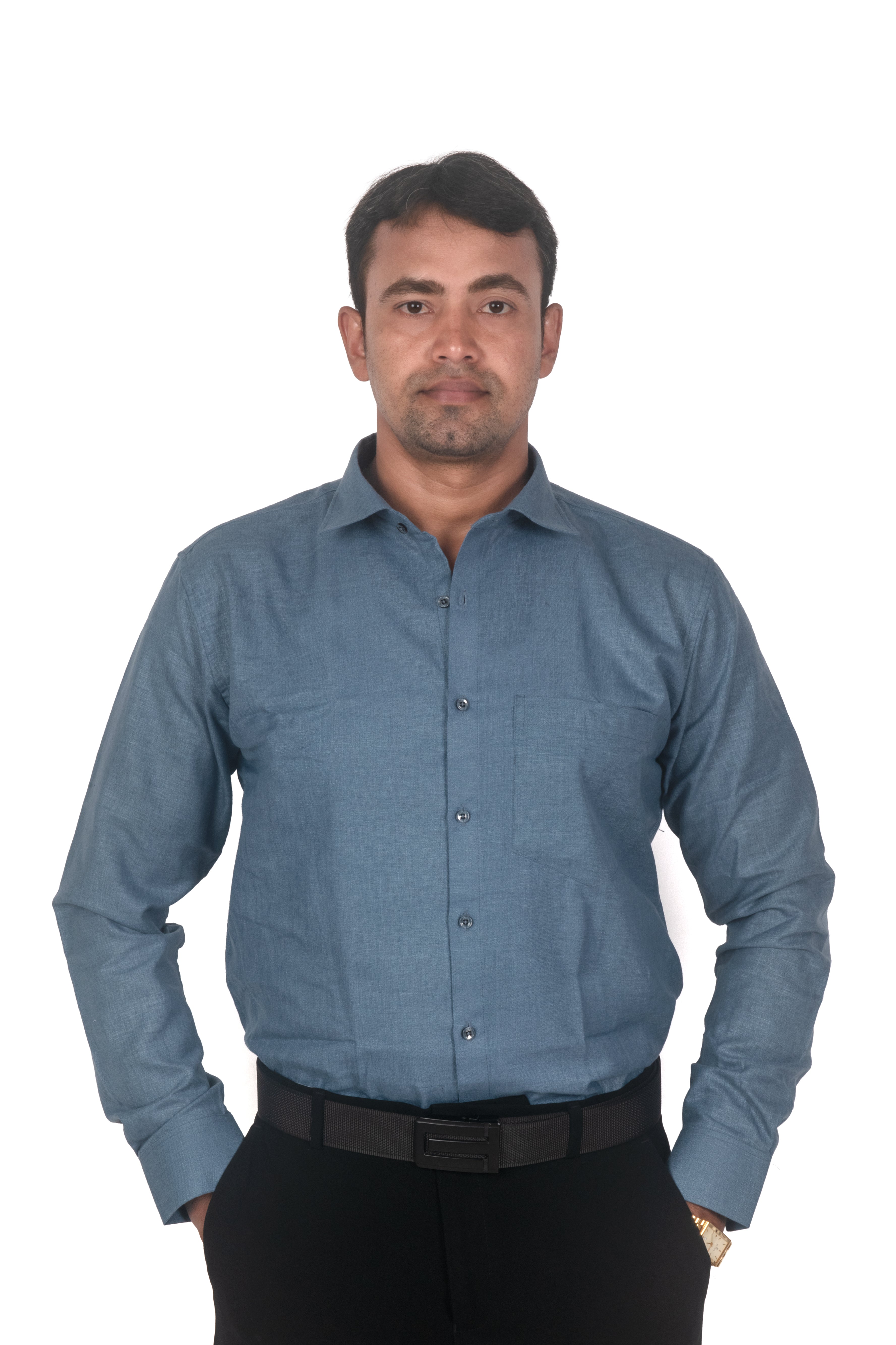 A man wearing a slate blue long-sleeve button-down shirt and black trousers, standing against a plain white background.