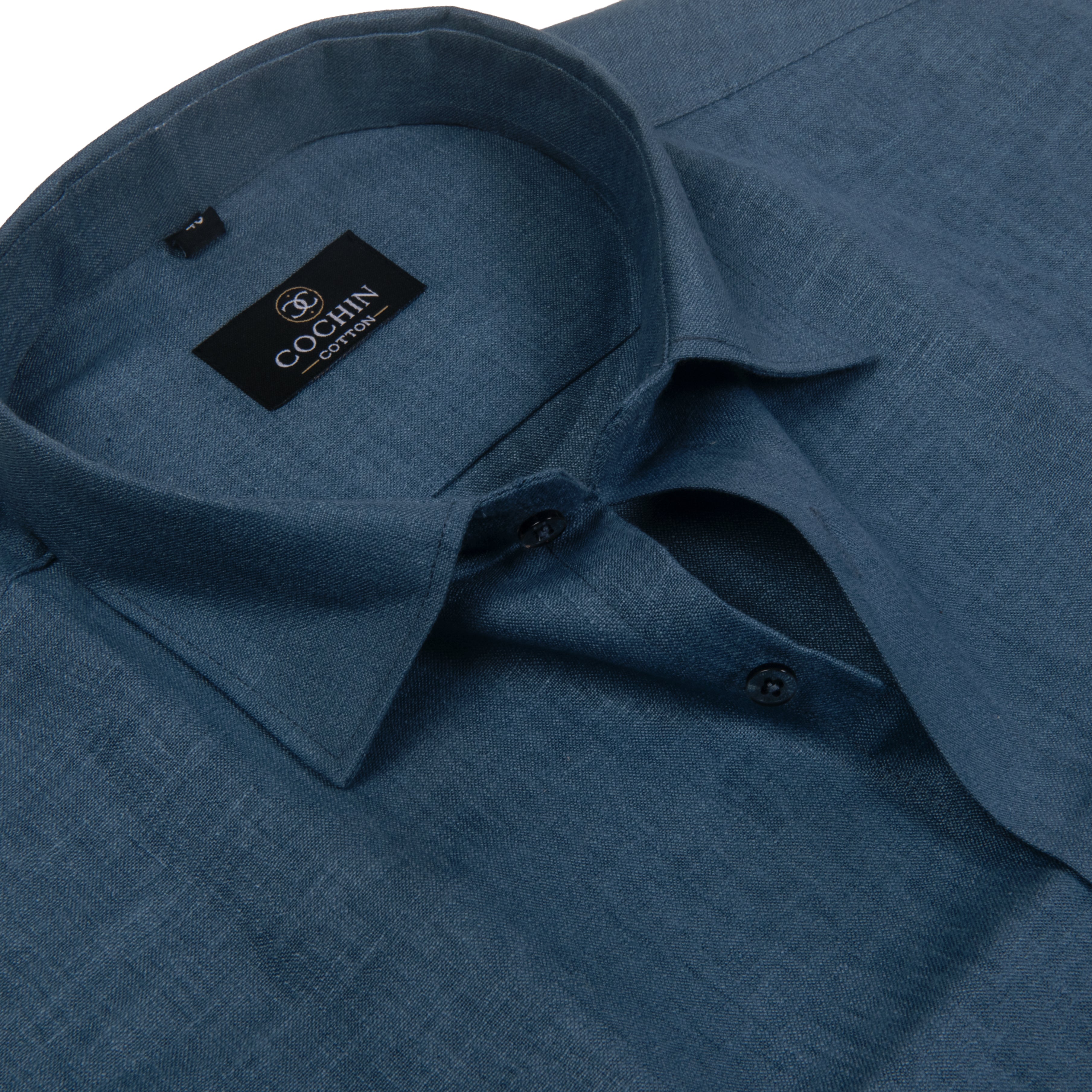 A close-up of a blue textured linen shirt by COGNIN, showing the collar, inner label, and button details against a white background.
