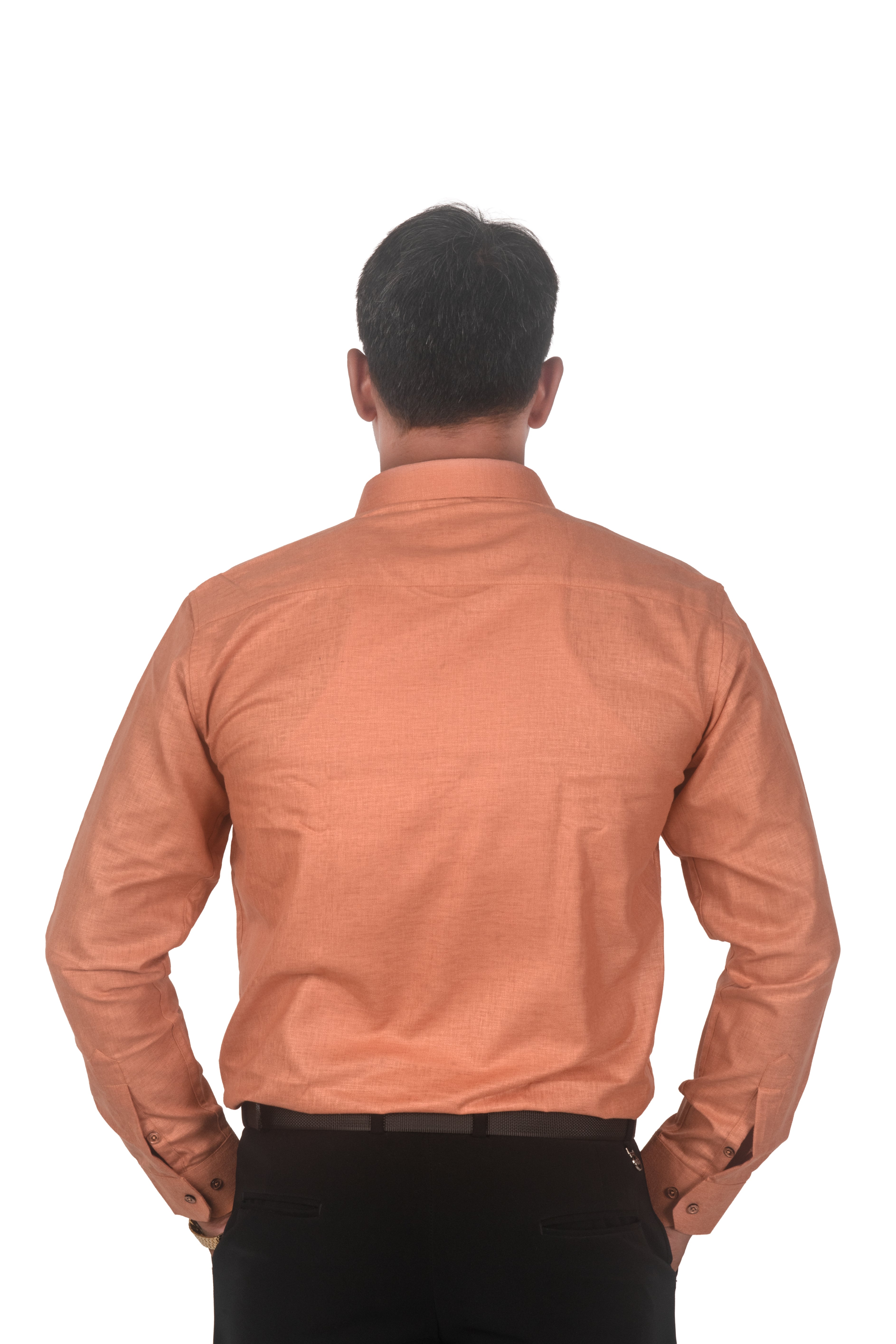 A man viewed from behind wearing a peach-colored long-sleeve button-up shirt and black trousers, standing against a plain white background.