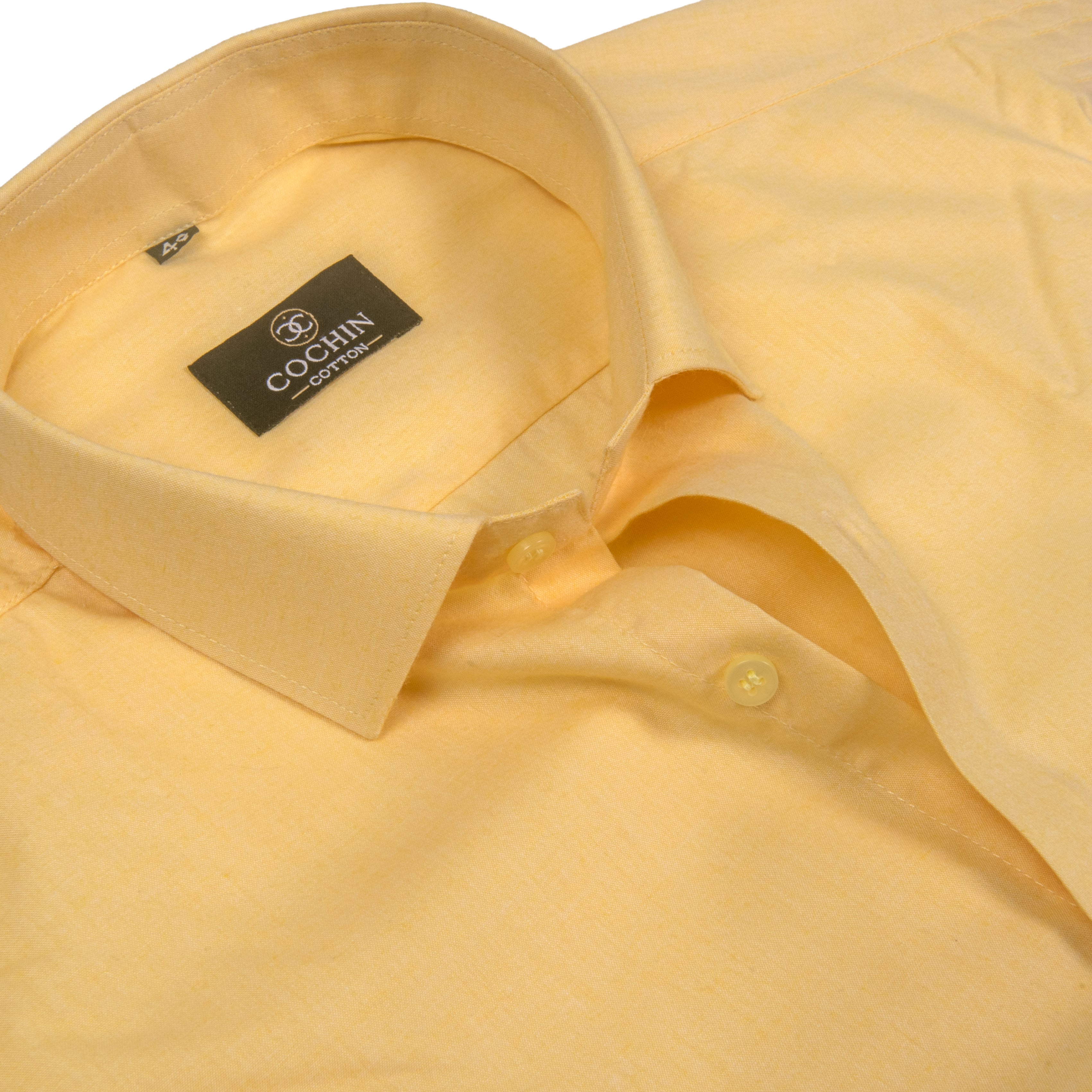 A close-up of a light yellow linen shirt by Cocin Couture, showing the collar, inner neck label, and button placket.