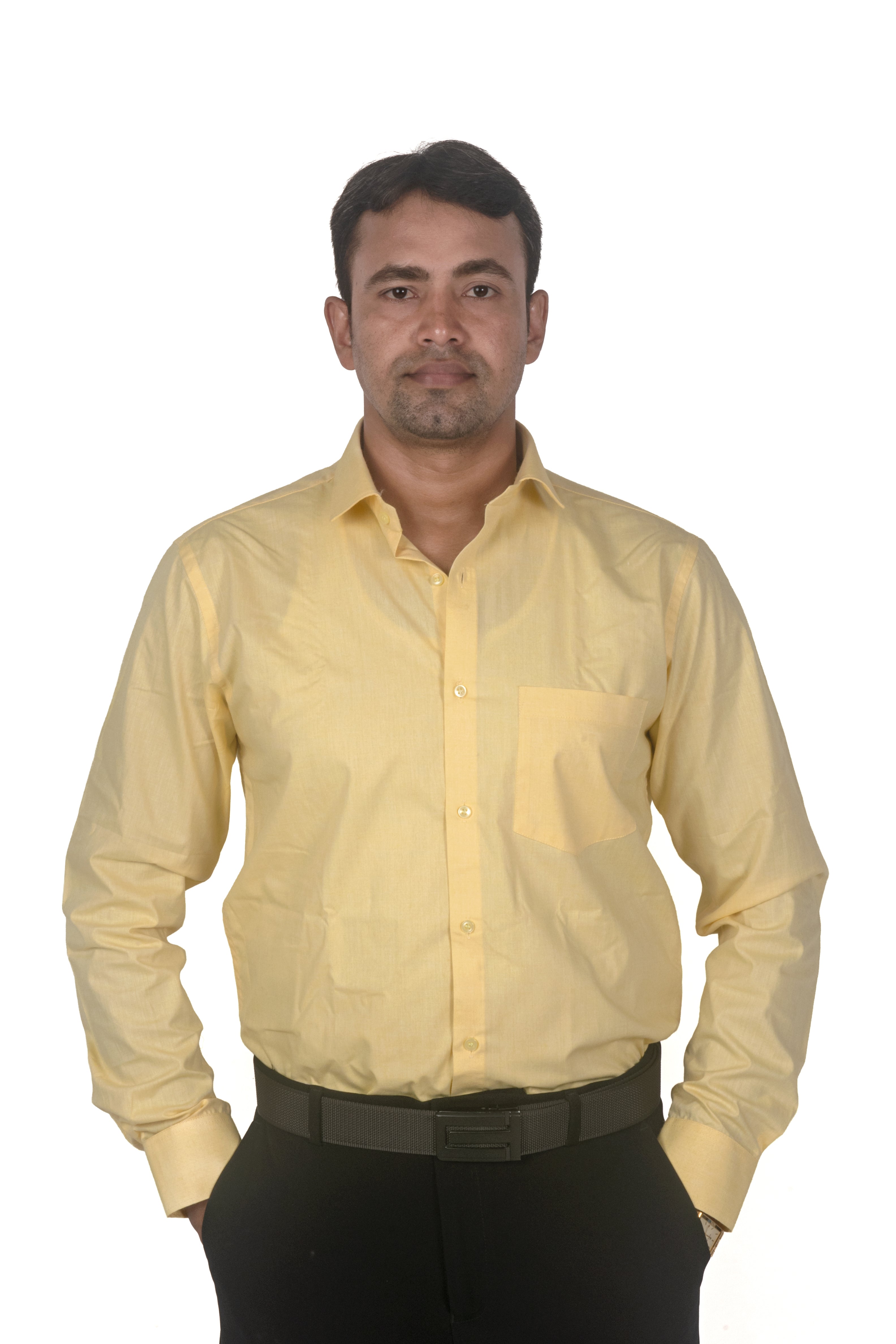 A man wearing a light yellow long-sleeve button-down shirt and black trousers, standing against a plain white background.