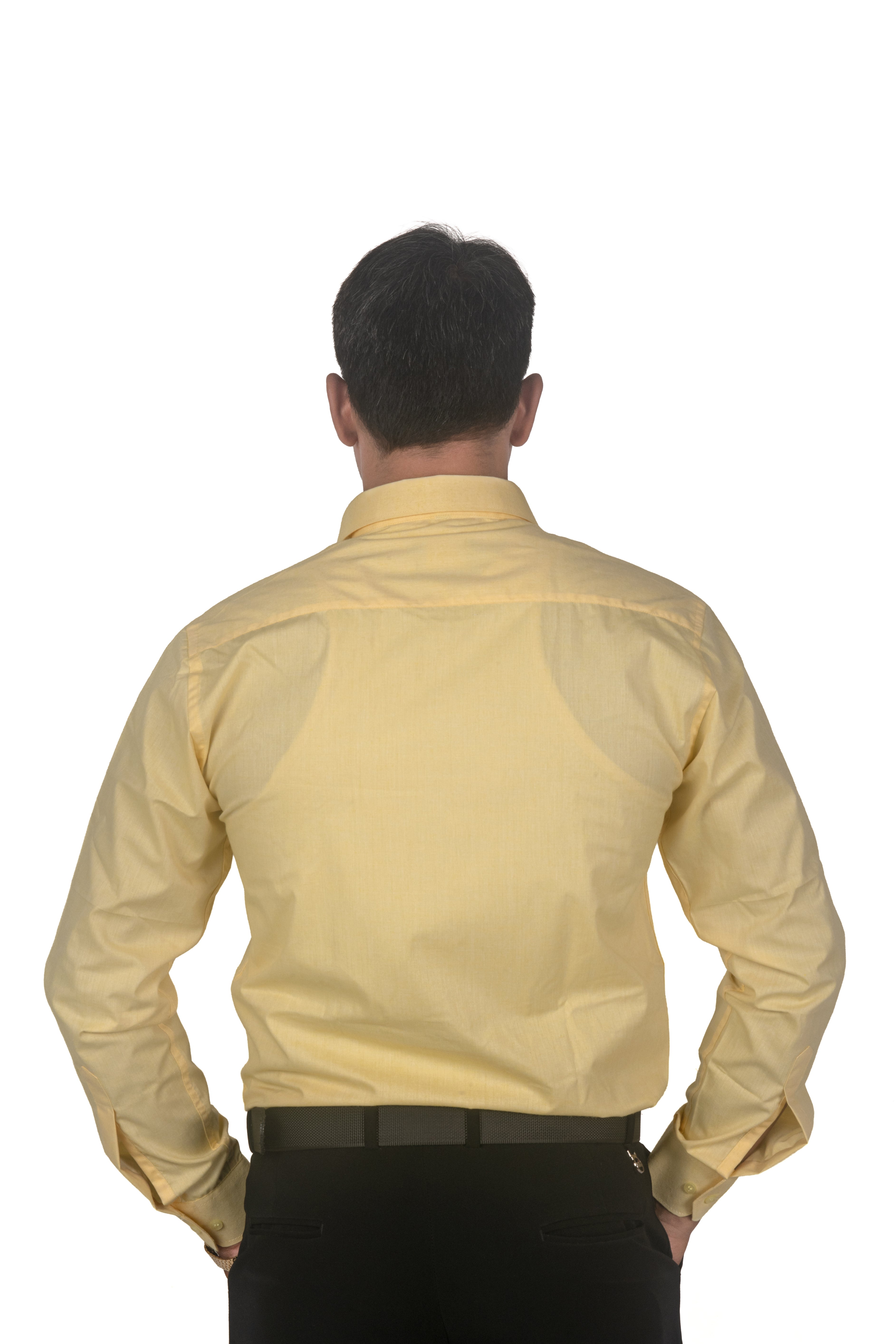 A man viewed from behind wearing a pale yellow long-sleeve dress shirt and black trousers, standing against a plain white background.